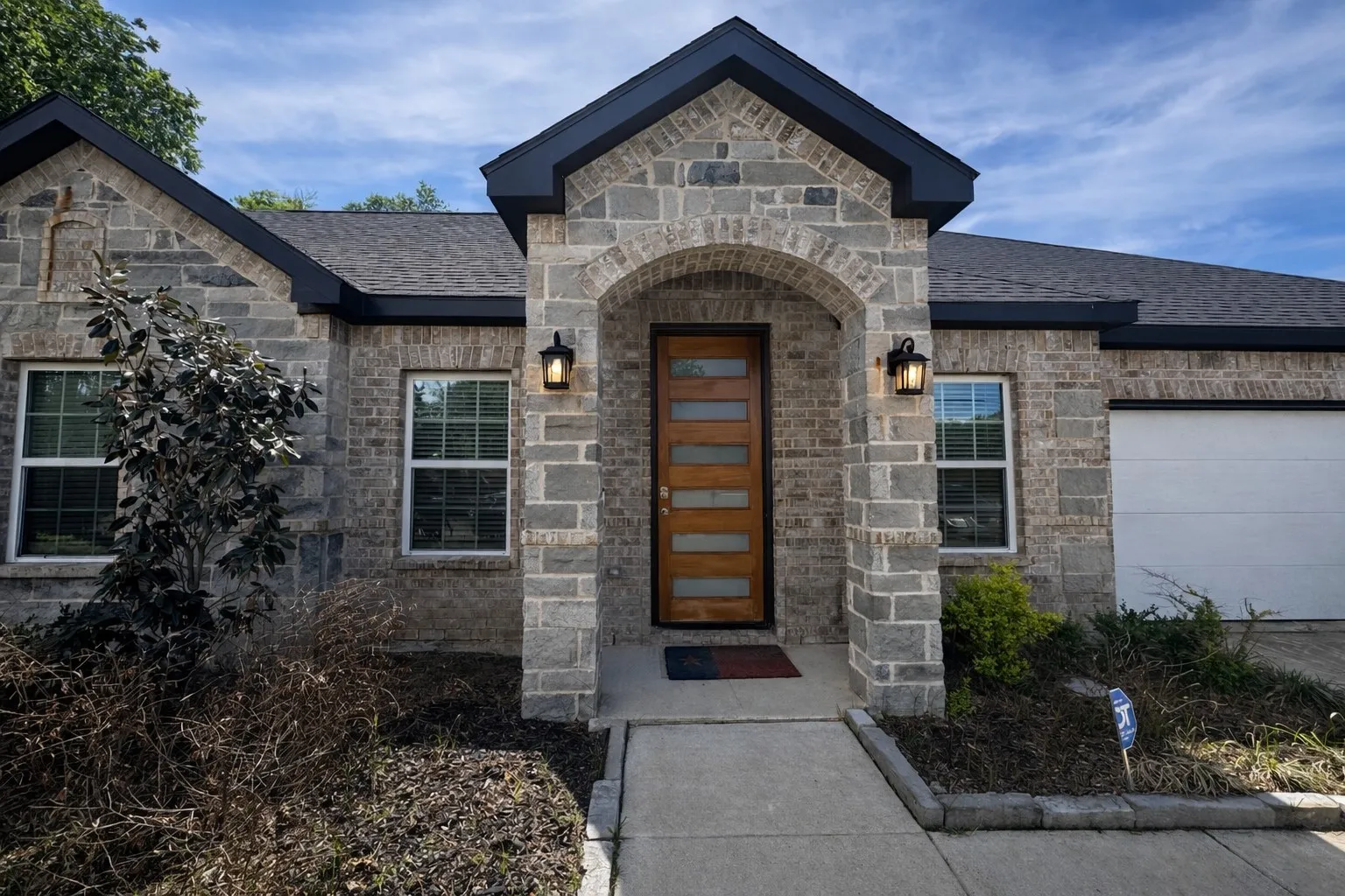 Doorway to property featuring an attached garage and stone siding