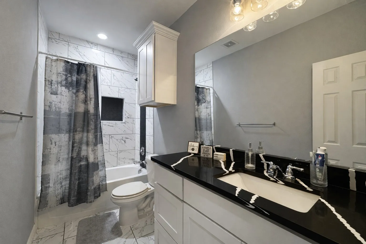 Bathroom featuring vanity, shower / bath combination with curtain, and light marble finish flooring