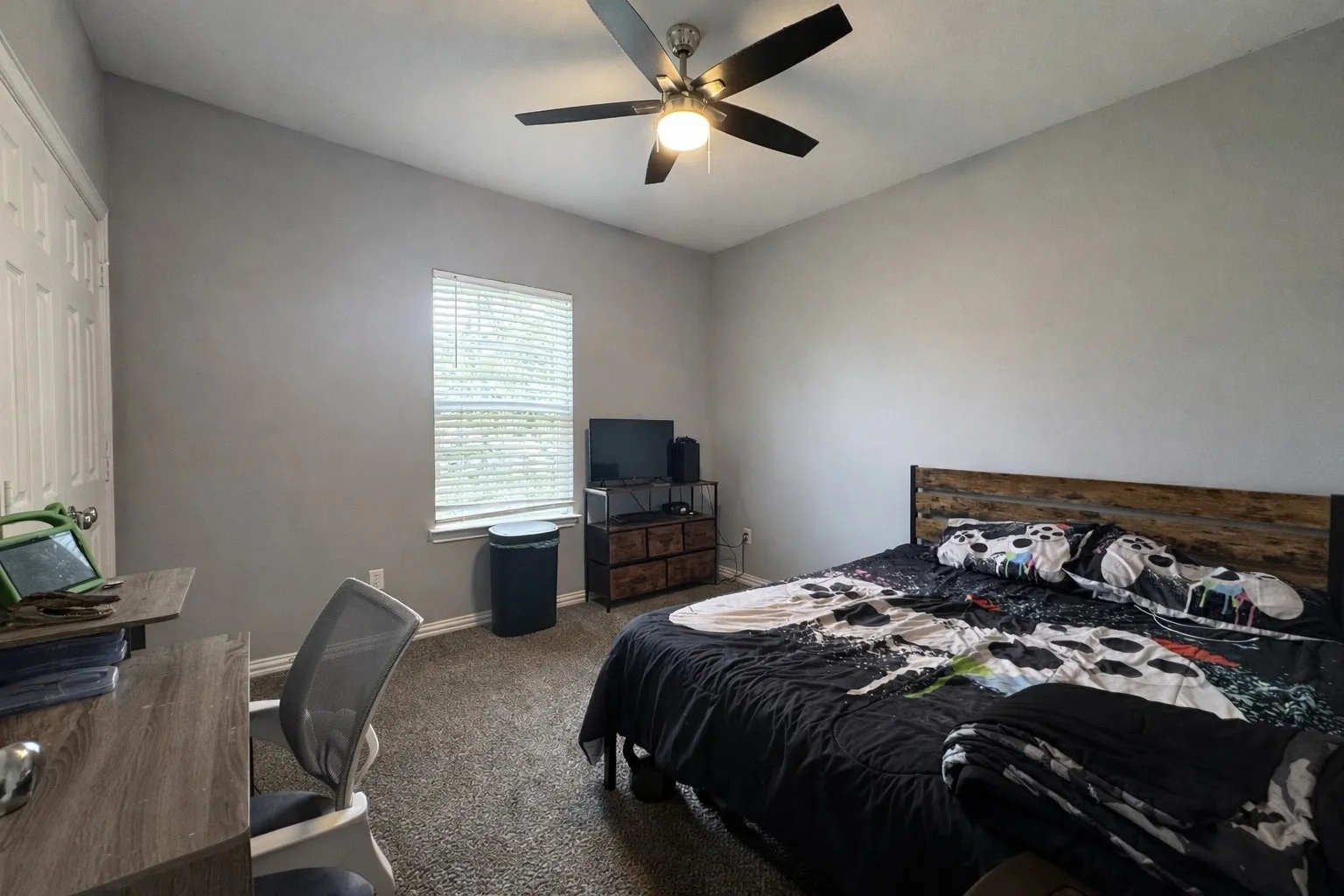 Bedroom with dark carpet, an office area, and a ceiling fan