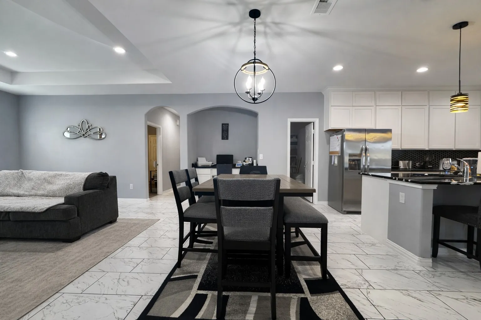 Dining space with arched walkways, a chandelier, a tray ceiling, and light marble finish flooring