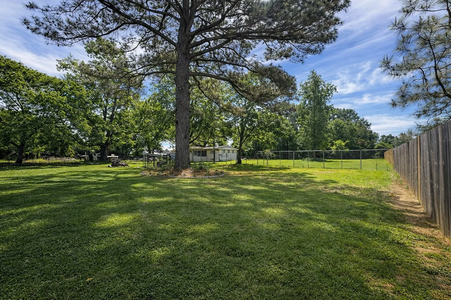 Fenced backyard featuring view of scattered trees