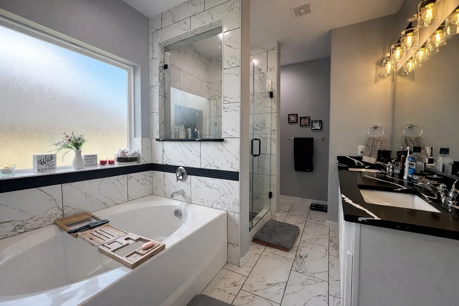 Bathroom featuring light marble finish flooring, double vanity, a bath, and a marble finish shower