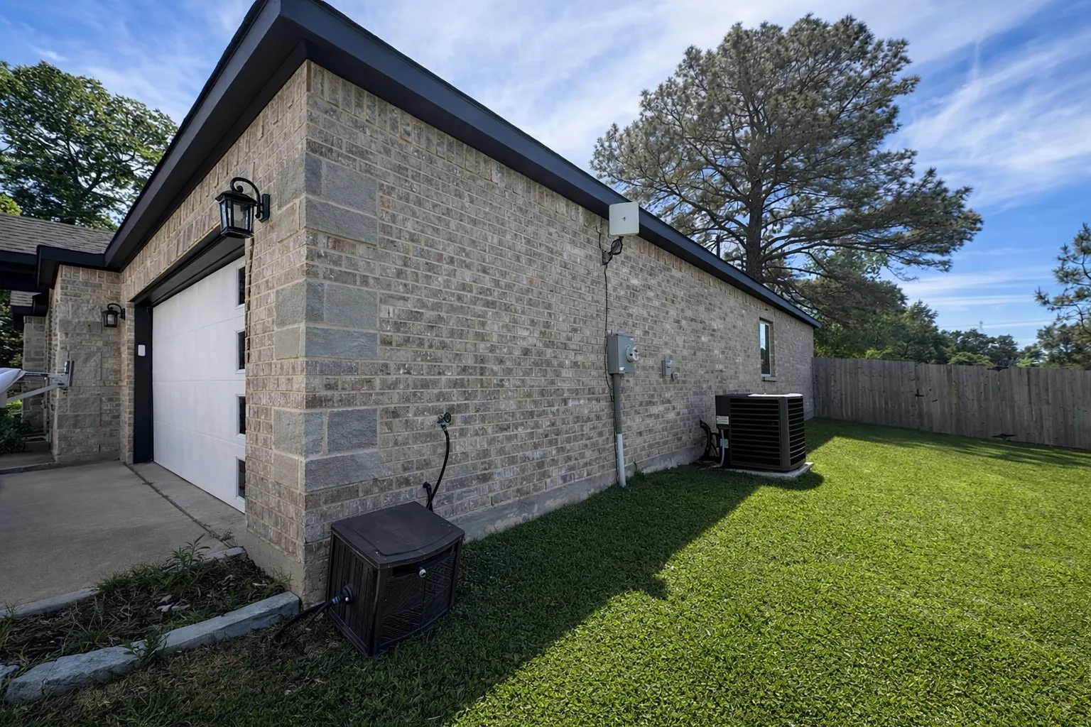 View of property exterior featuring an attached garage, brick siding, and driveway