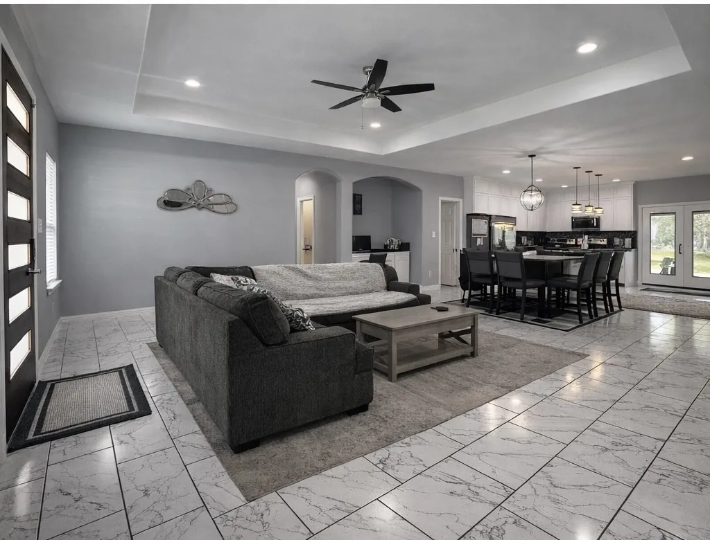 Living area featuring arched walkways, a raised ceiling, french doors, ceiling fan, and recessed lighting