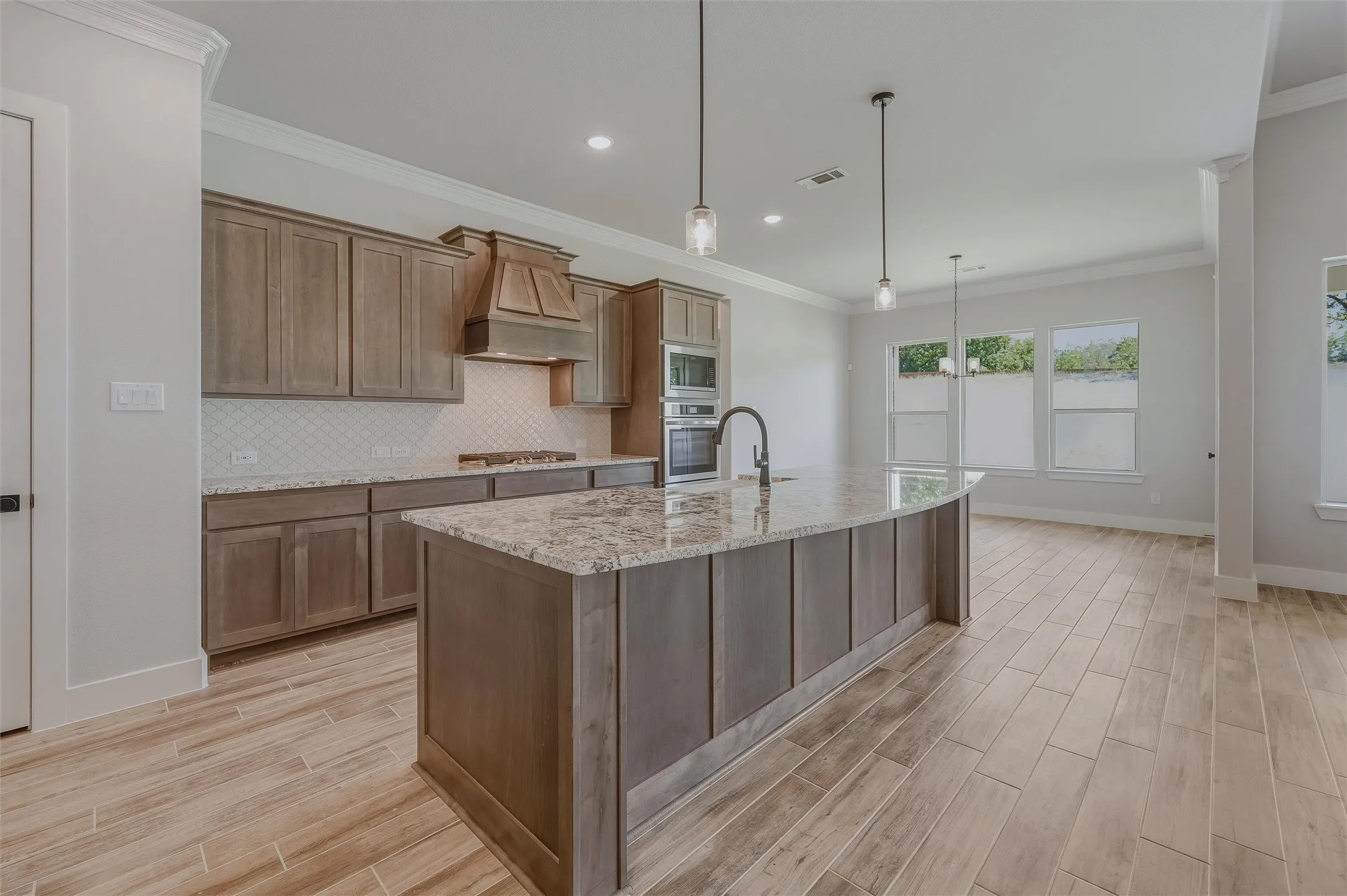 Kitchen featuring a curved central island with an undermount sink and pendant lighting