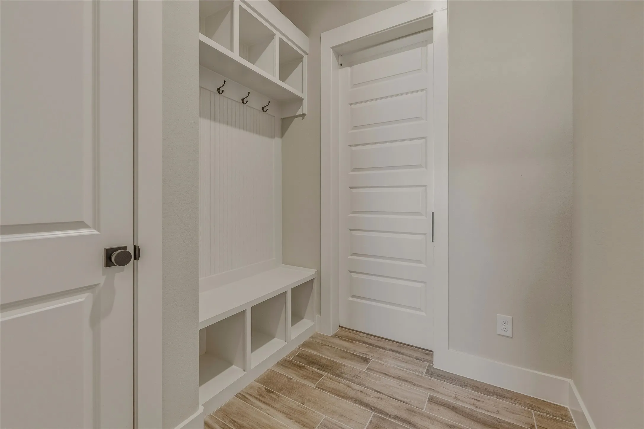 Built-in mudroom bench with cubby storage, upper shelving, and coat hooks