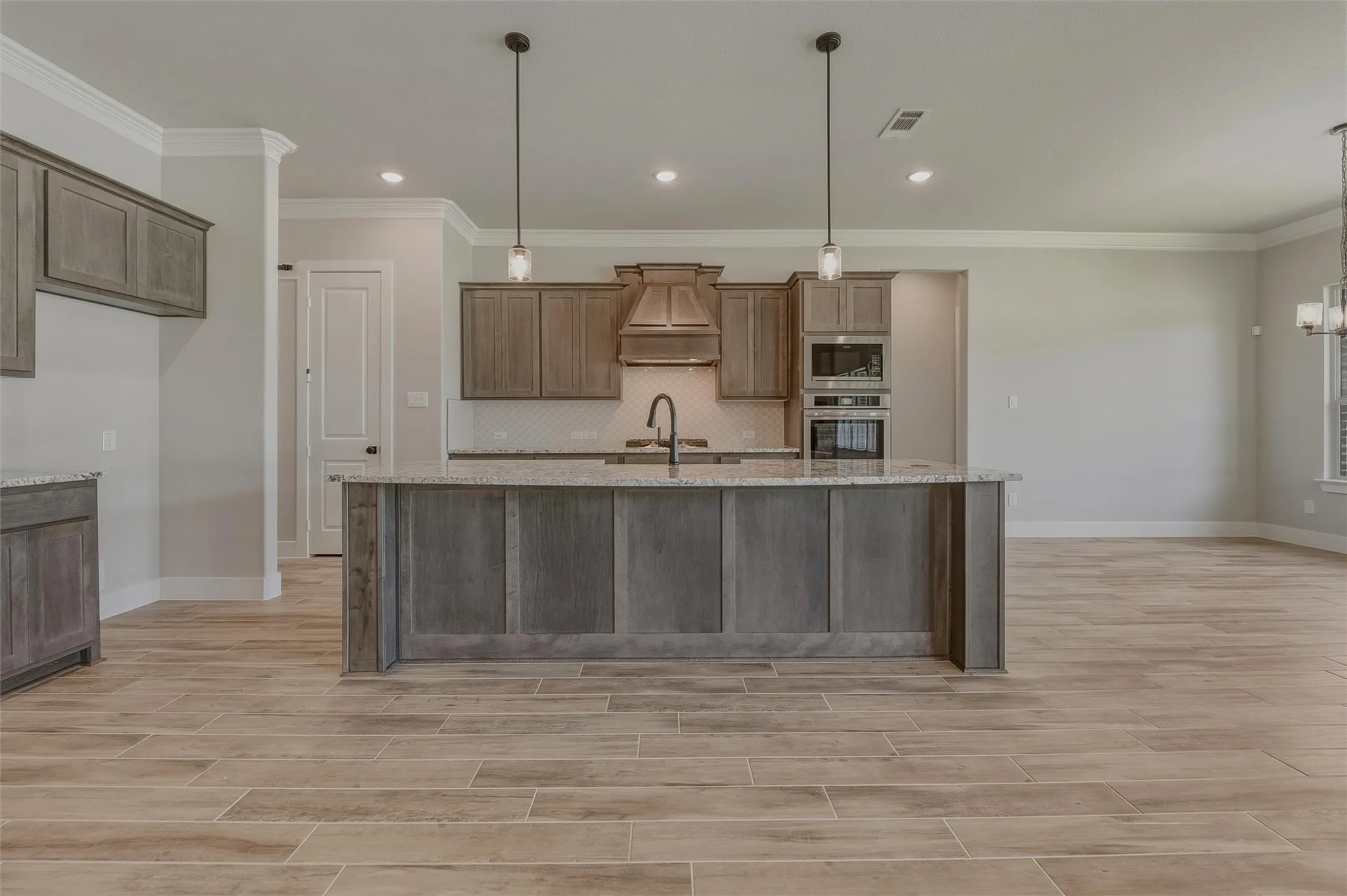 Kitchen featuring a central island with paneling, pendant lighting, and granite countertops