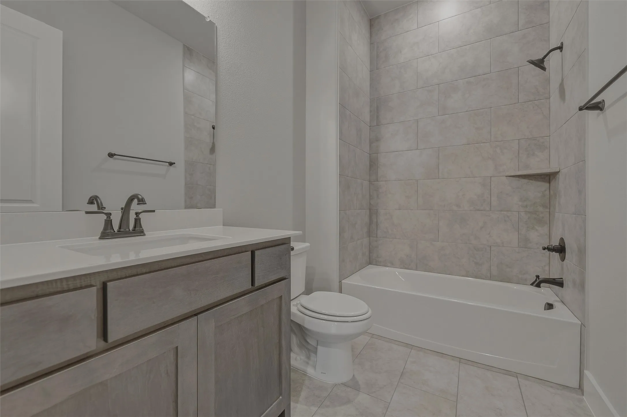 Bathroom featuring a light-toned wood-finish vanity with a white countertop, undermount sink, and dark-finished faucet