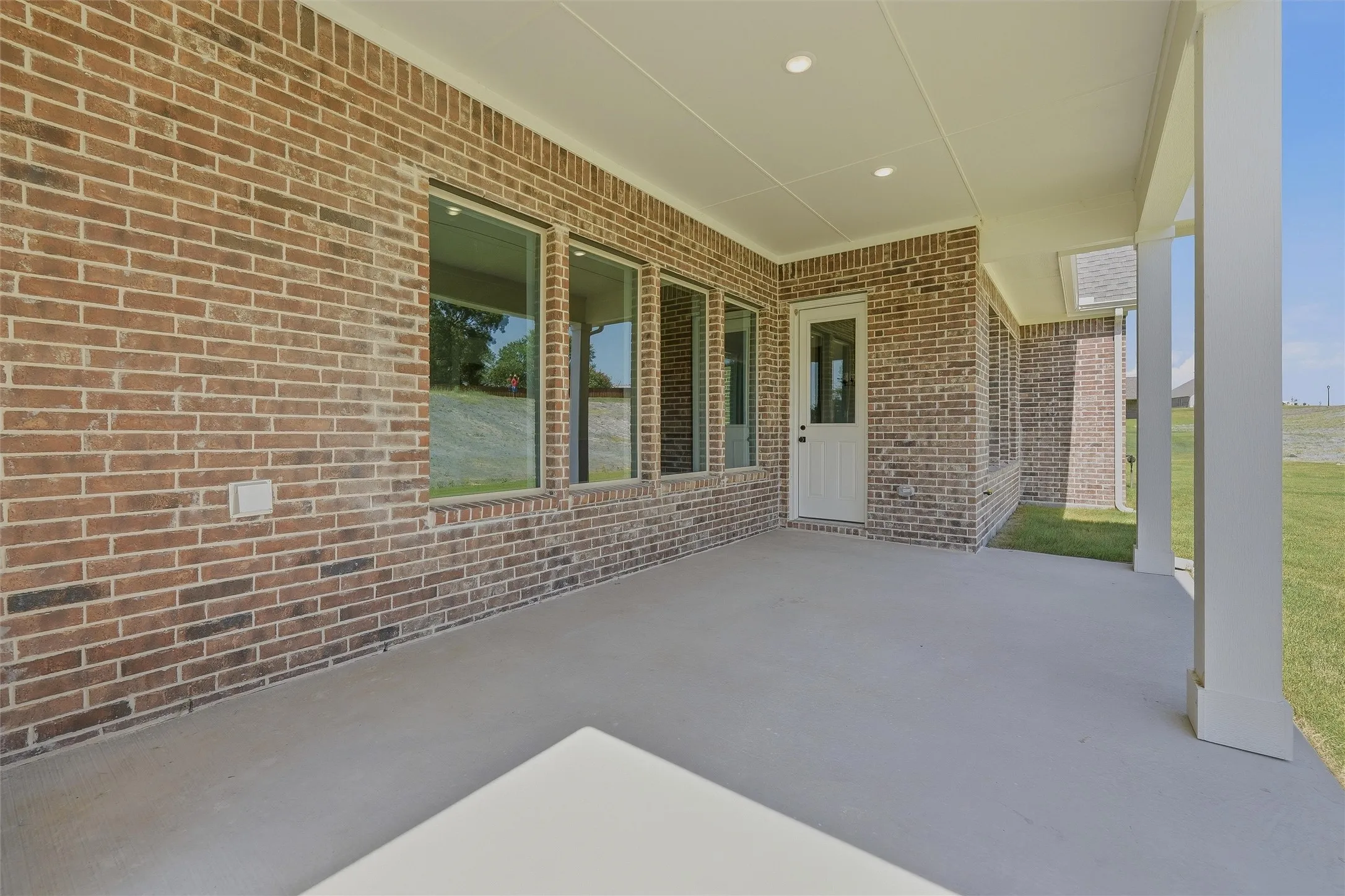 Expansive covered patio featuring a concrete surface and brick exterior walls