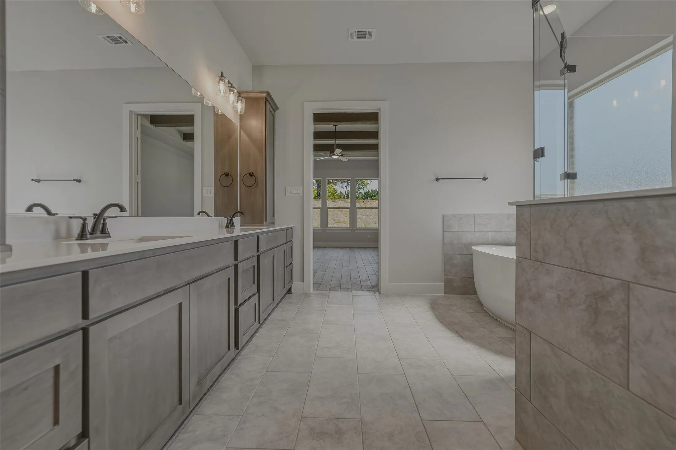 Bathroom featuring a dual vanity with light gray cabinetry, white countertops, and matte black fixtures