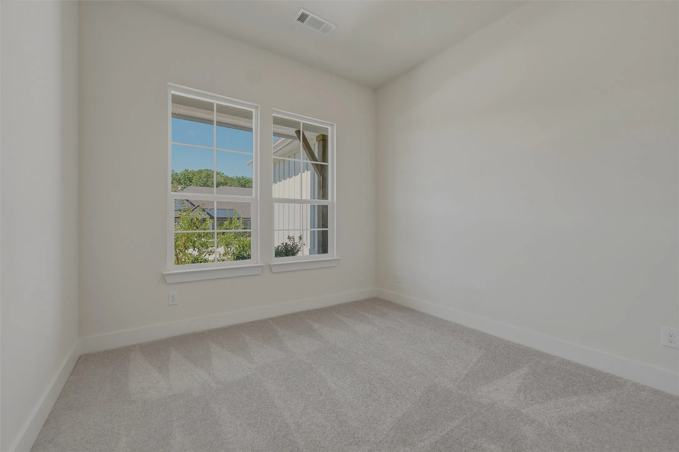 Room with light gray carpeting, neutral wall paint, and two double-hung windows