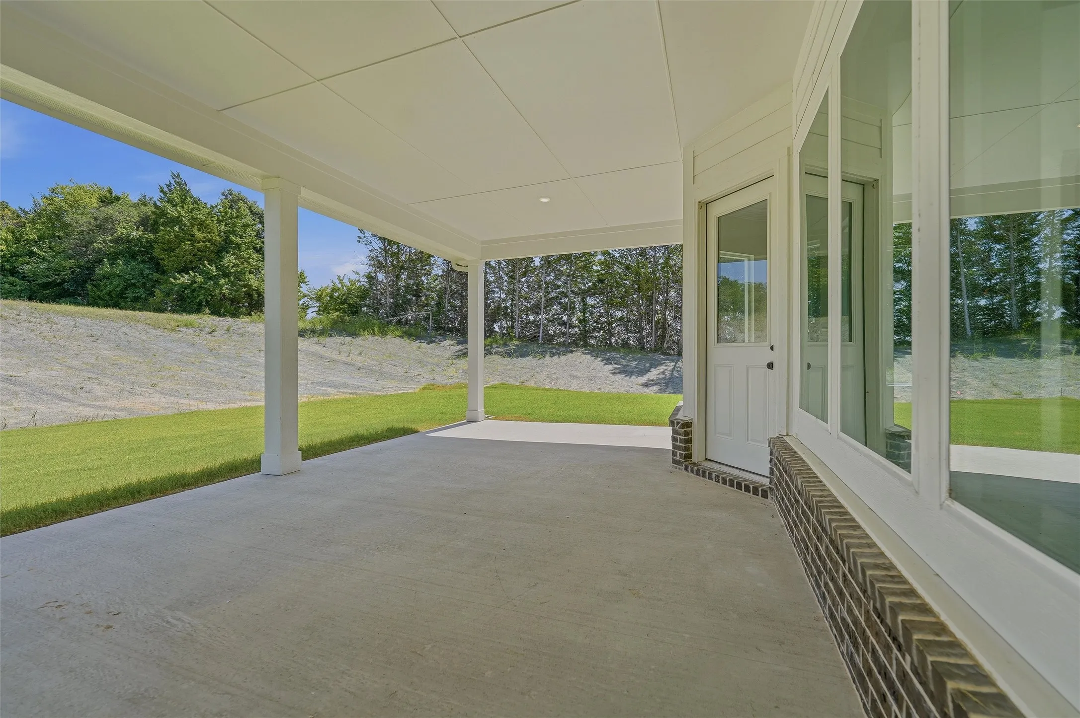 Spacious covered patio with a concrete surface and white support columns