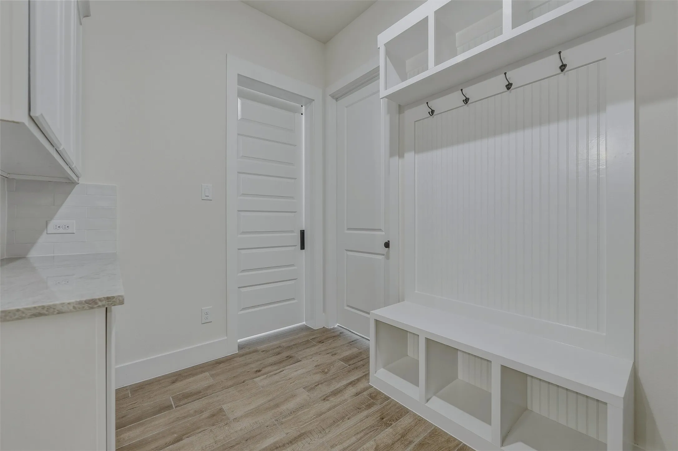 Built-in mudroom bench with cubby storage, upper shelving, and coat hooks