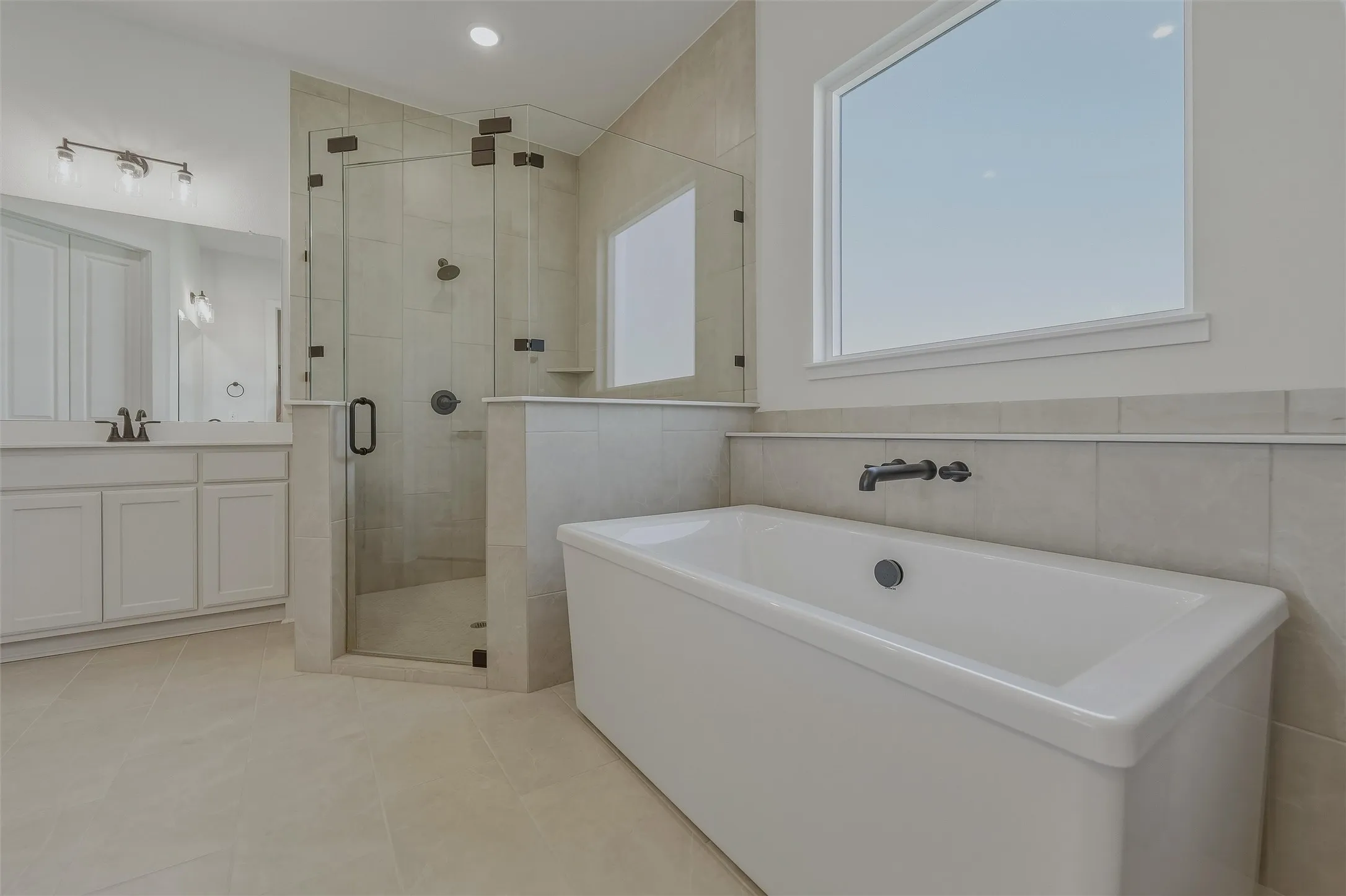 Freestanding soaking tub with a wall-mounted black faucet, set against a tiled accent wall