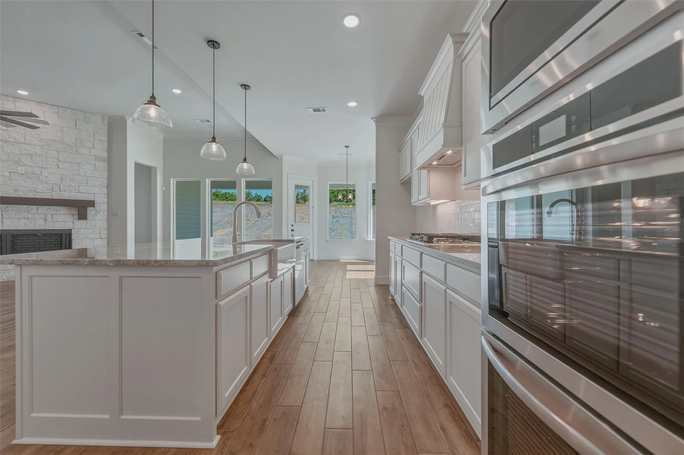 Gourmet kitchen featuring stainless steel double ovens, a built-in gas cooktop, and a matching range hood