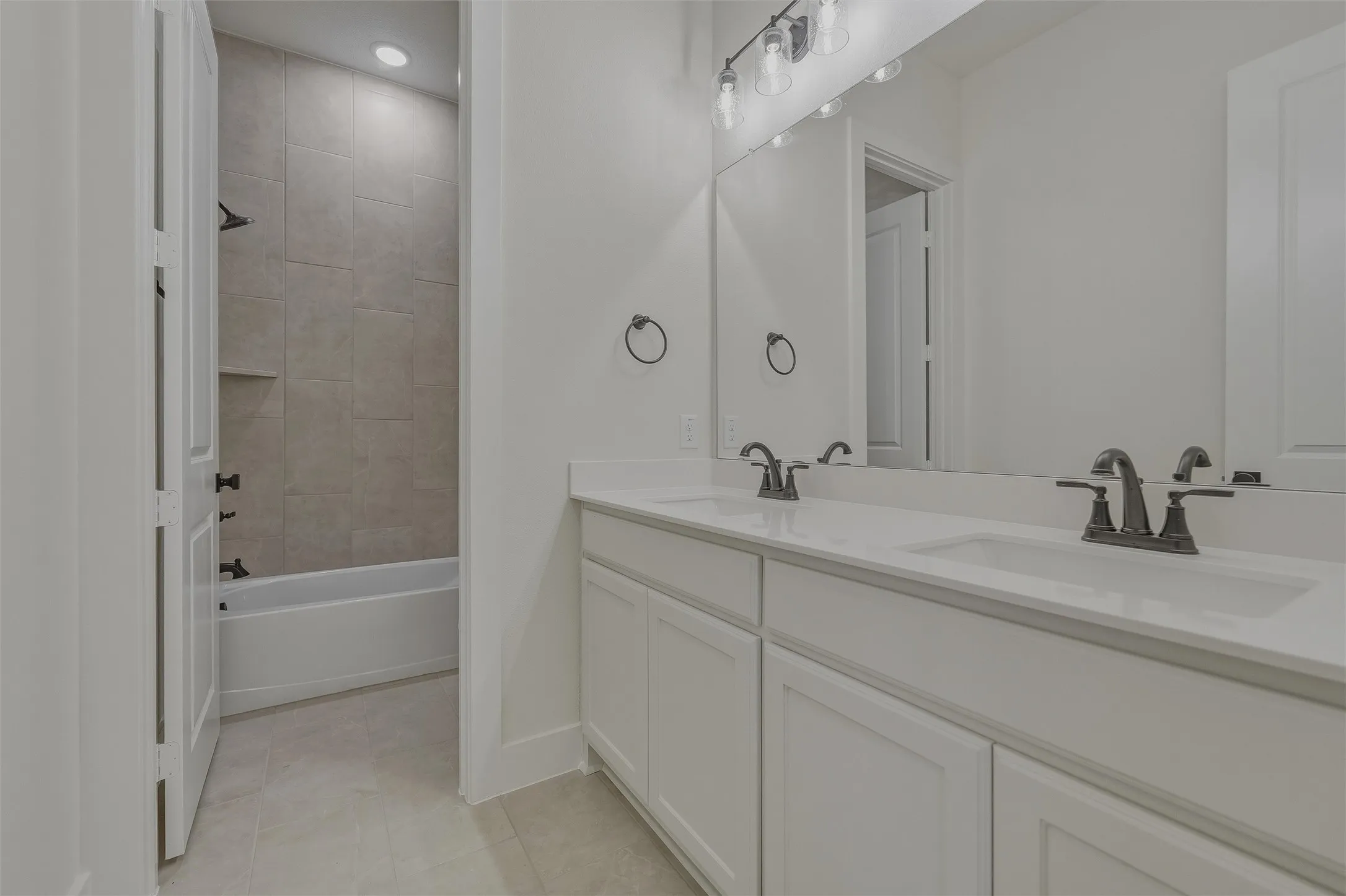 White double vanity featuring undermount sinks, dark bronze fixtures, and a large wall-mounted mirror