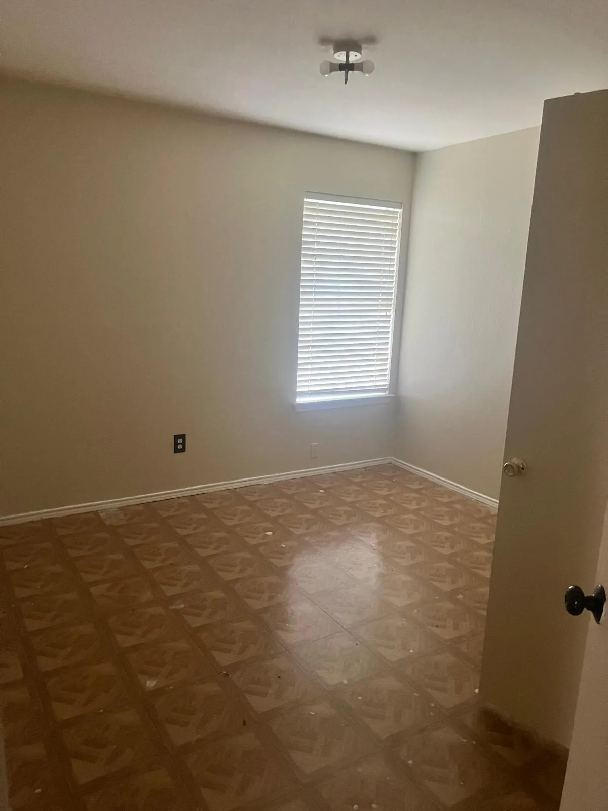 Room featuring wood-finish flooring, a window with horizontal blinds, and a flush mount ceiling light fixture