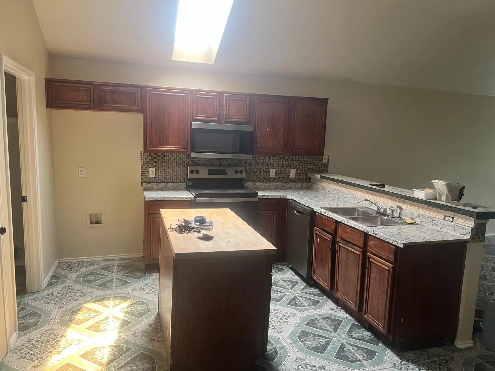 Kitchen featuring a central island with a wood-finish countertop, dark wood-finish cabinetry, and light-colored countertops