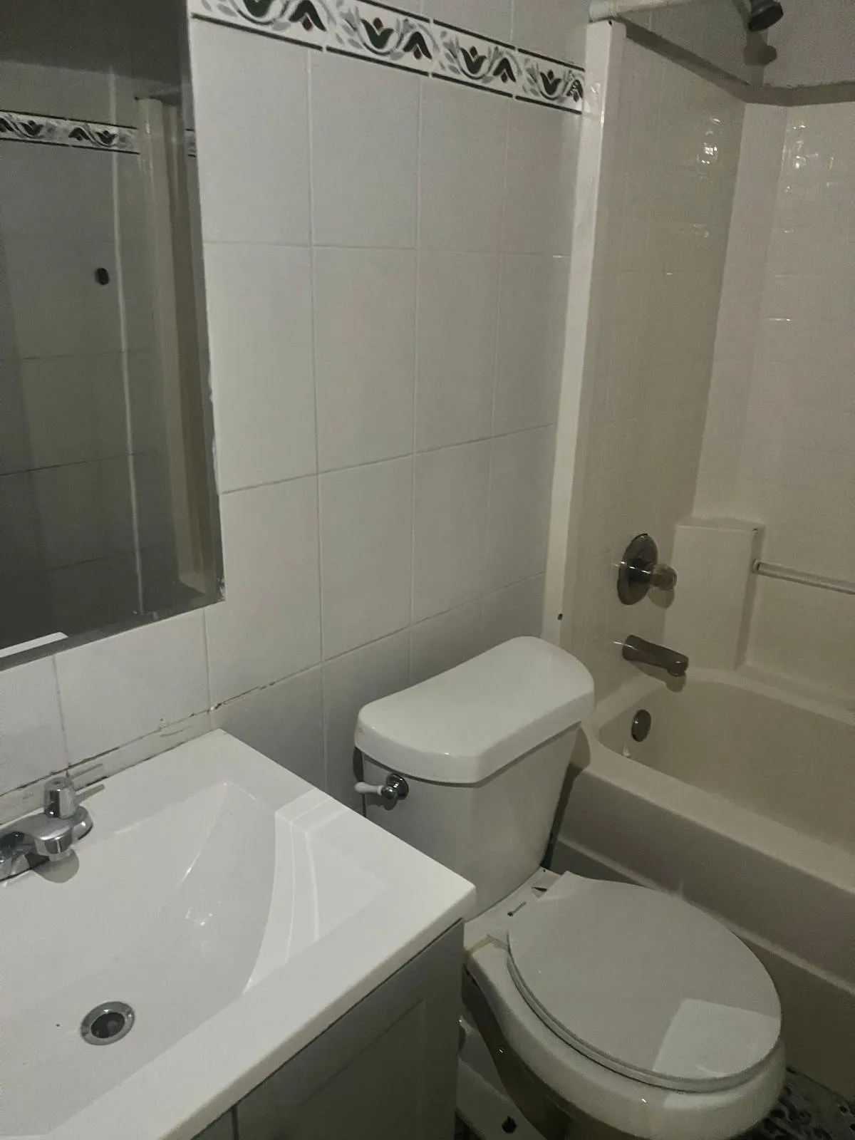 Bathroom featuring a white vanity with integrated sink, chrome faucet, wall-mounted mirror, and a toilet