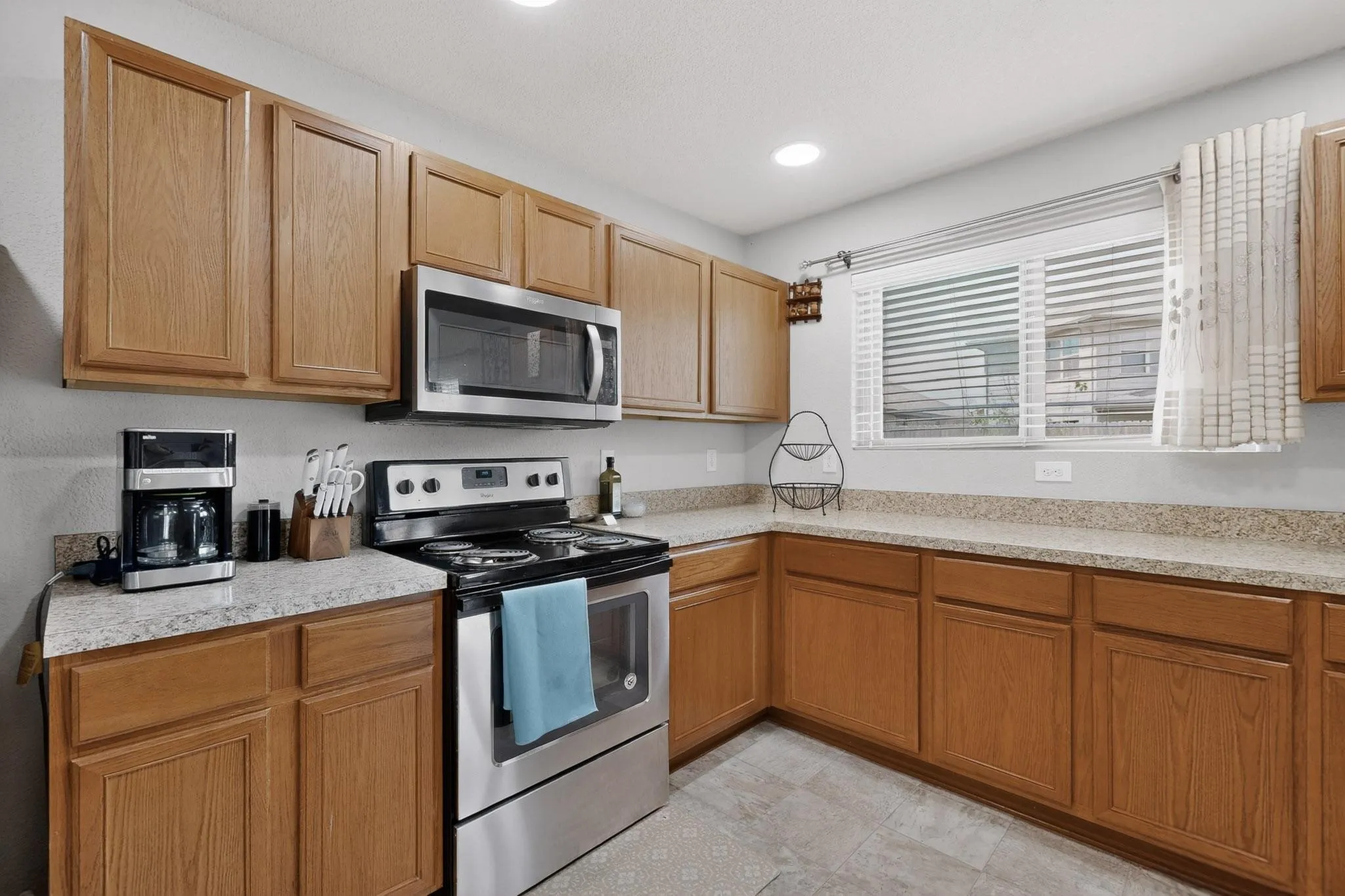 Kitchen with stainless steel appliances, light stone countertops, recessed lighting, and wood finish cabinetry