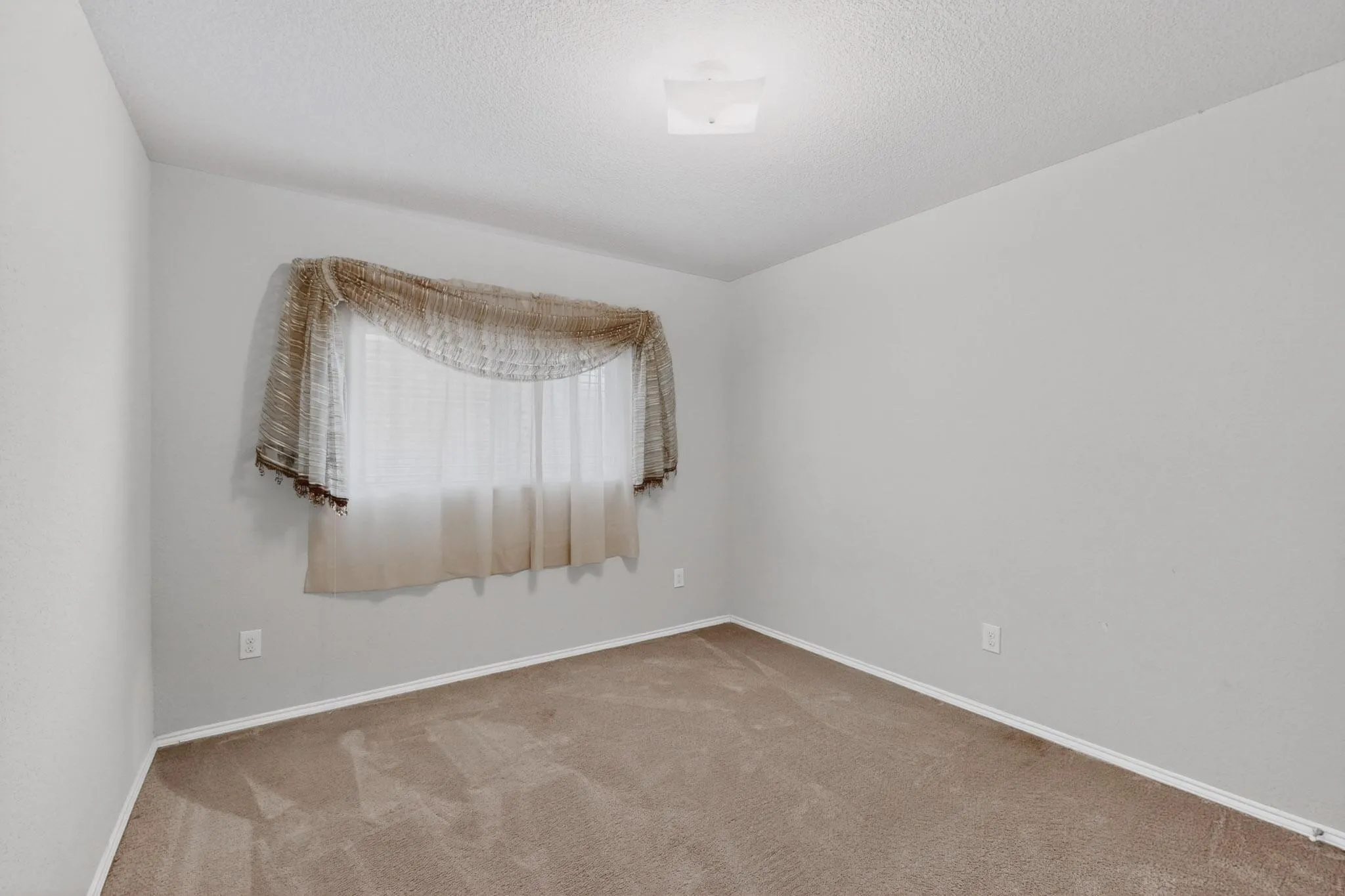 Spare room with light carpet and a textured ceiling