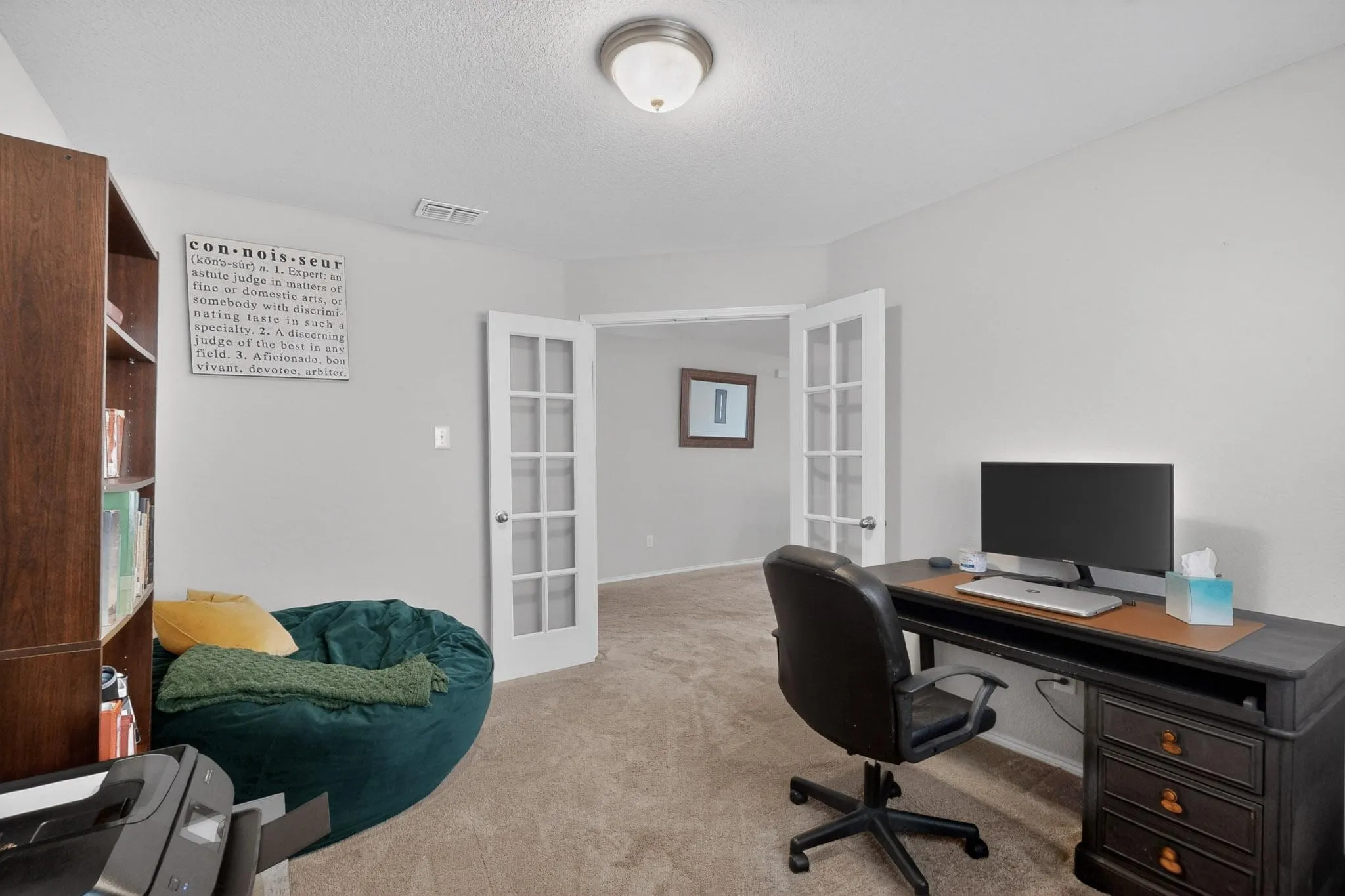 Home office with french doors, light colored carpet, and a textured ceiling