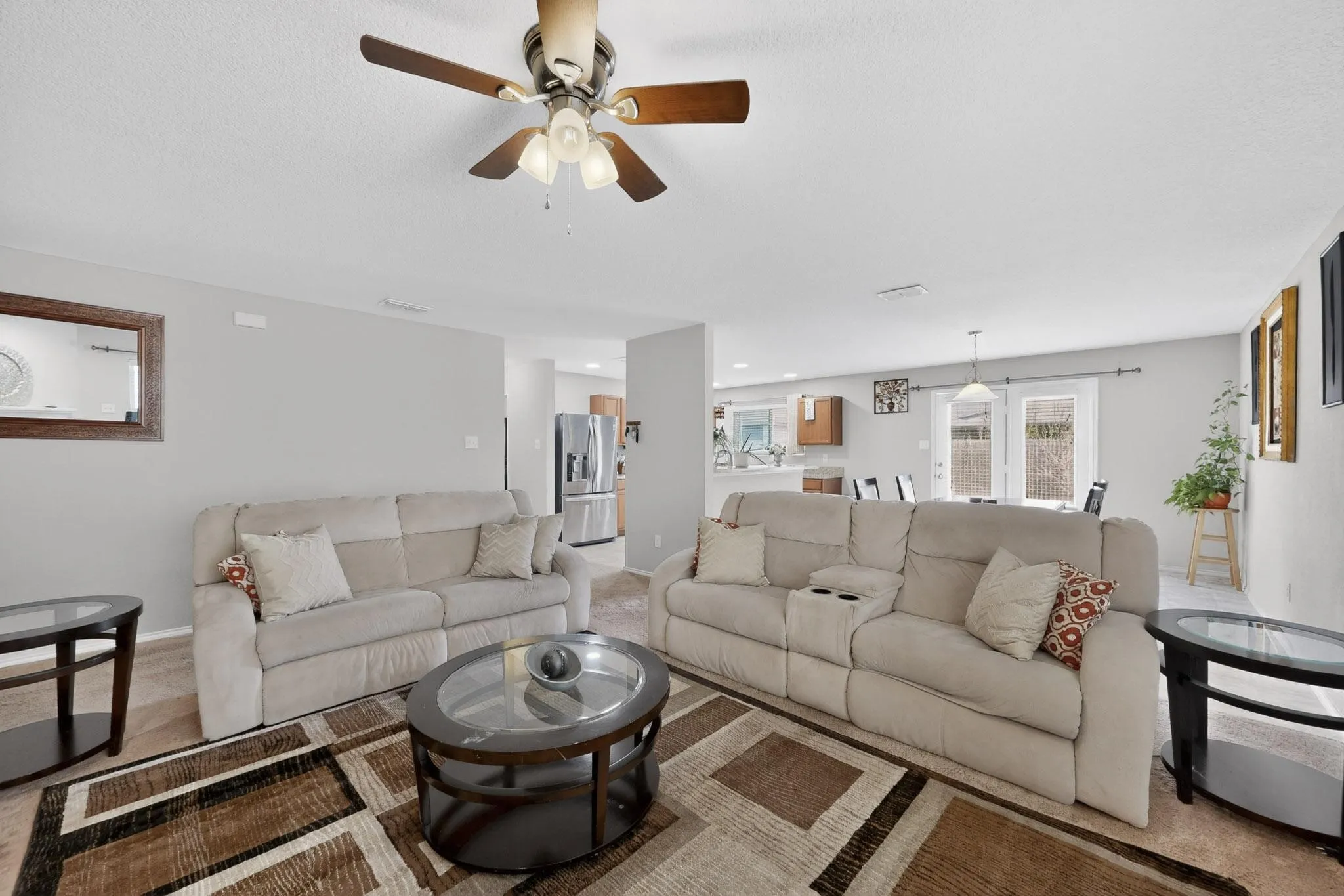 Carpeted living room featuring a ceiling fan and baseboards