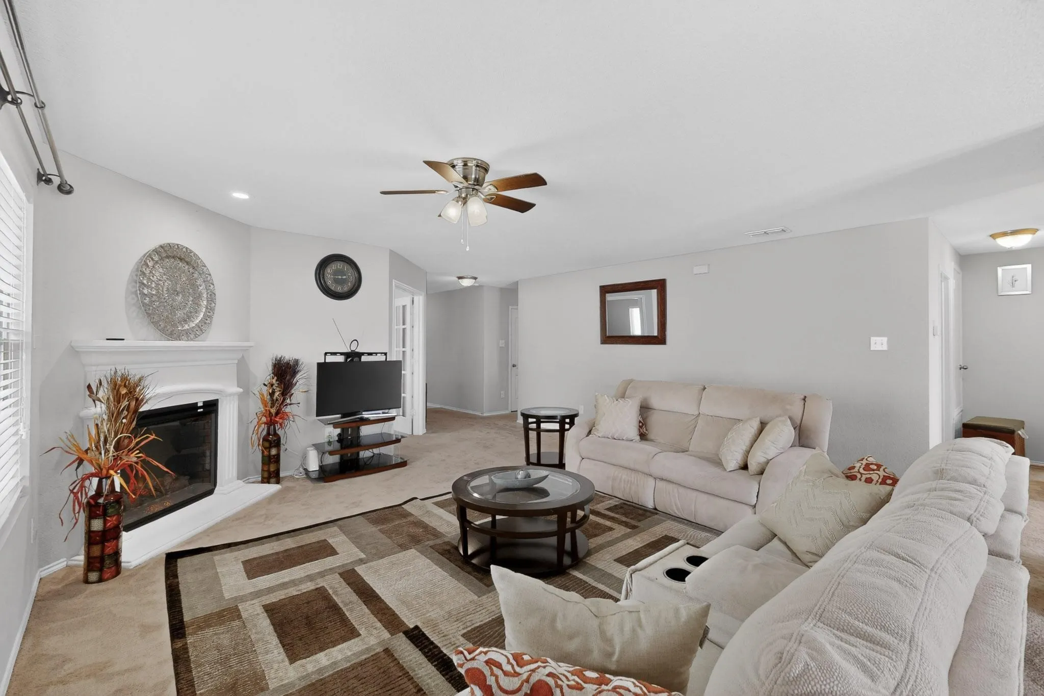 Living area with light carpet, a ceiling fan, a glass covered fireplace, and recessed lighting