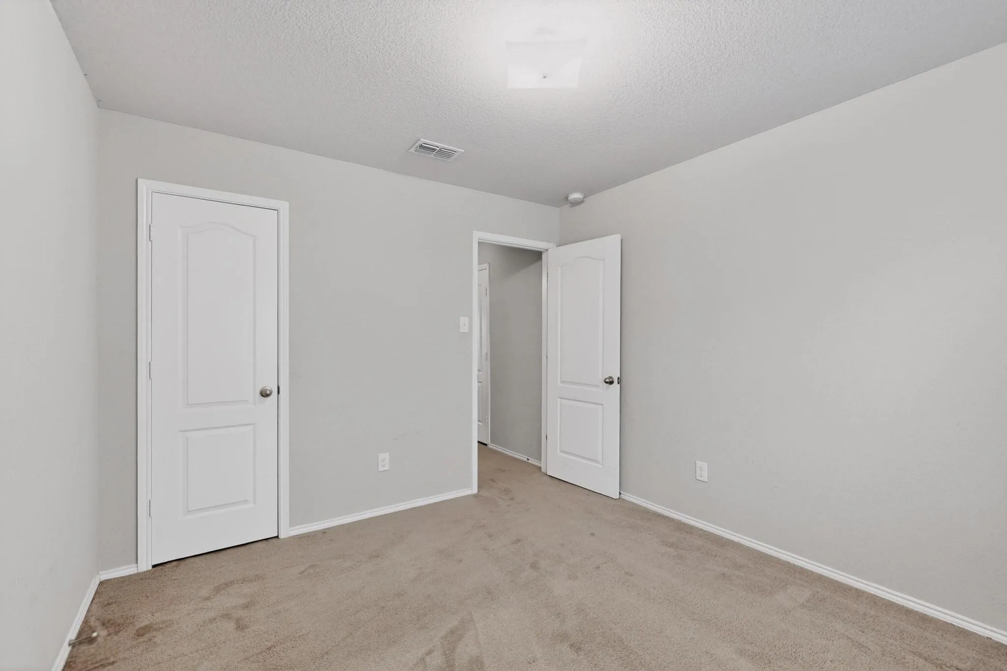 Unfurnished bedroom with light carpet and a textured ceiling