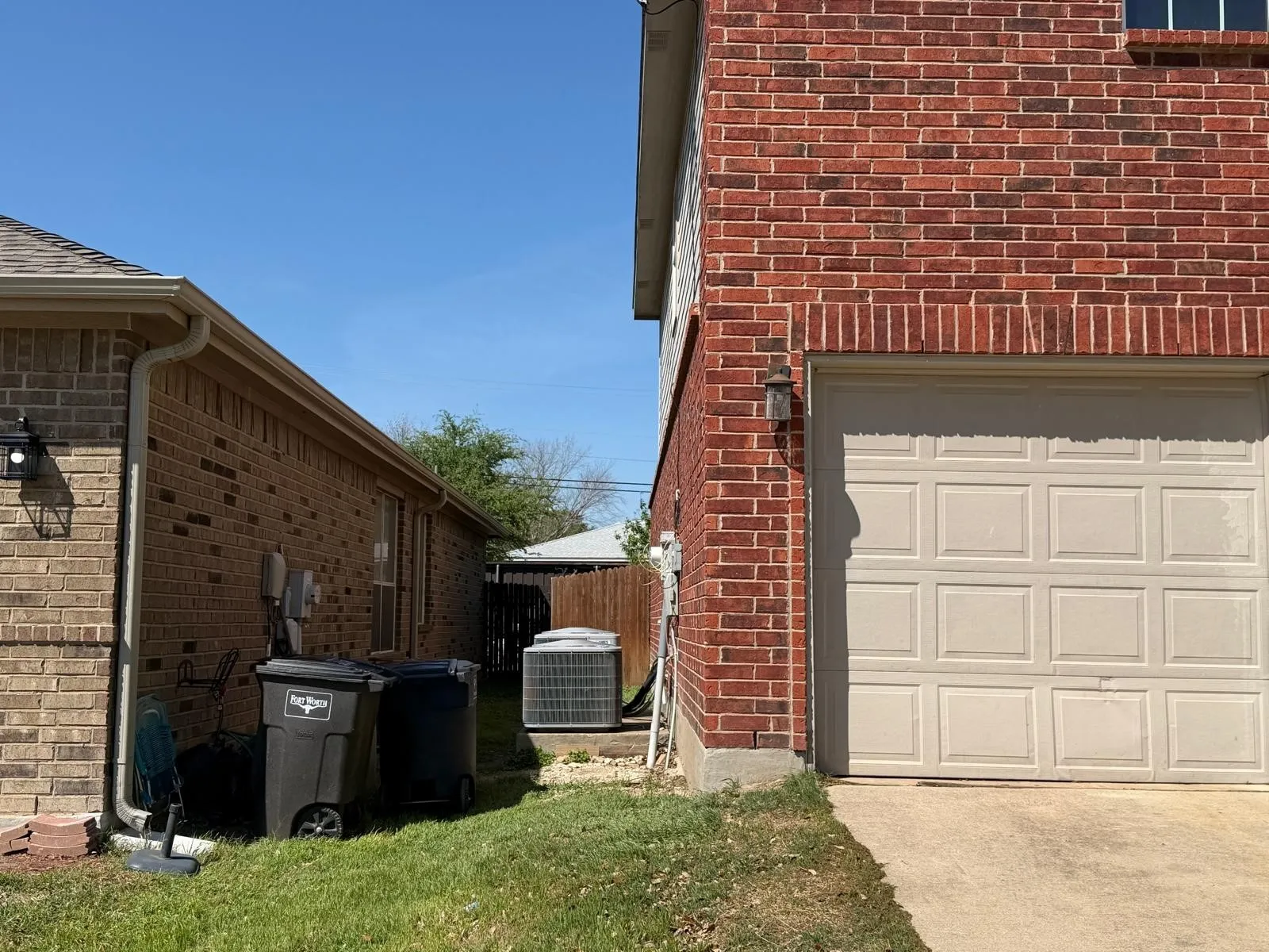 View of side of property with brick siding, a garage, and concrete driveway