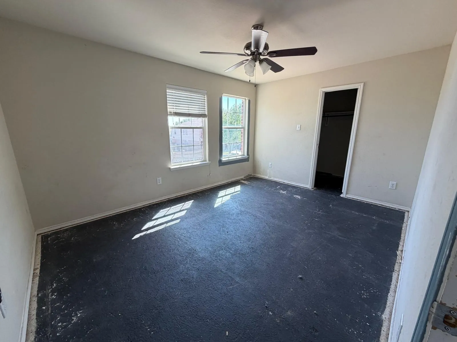 Unfurnished bedroom featuring a spacious closet, ceiling fan, and dark colored carpet