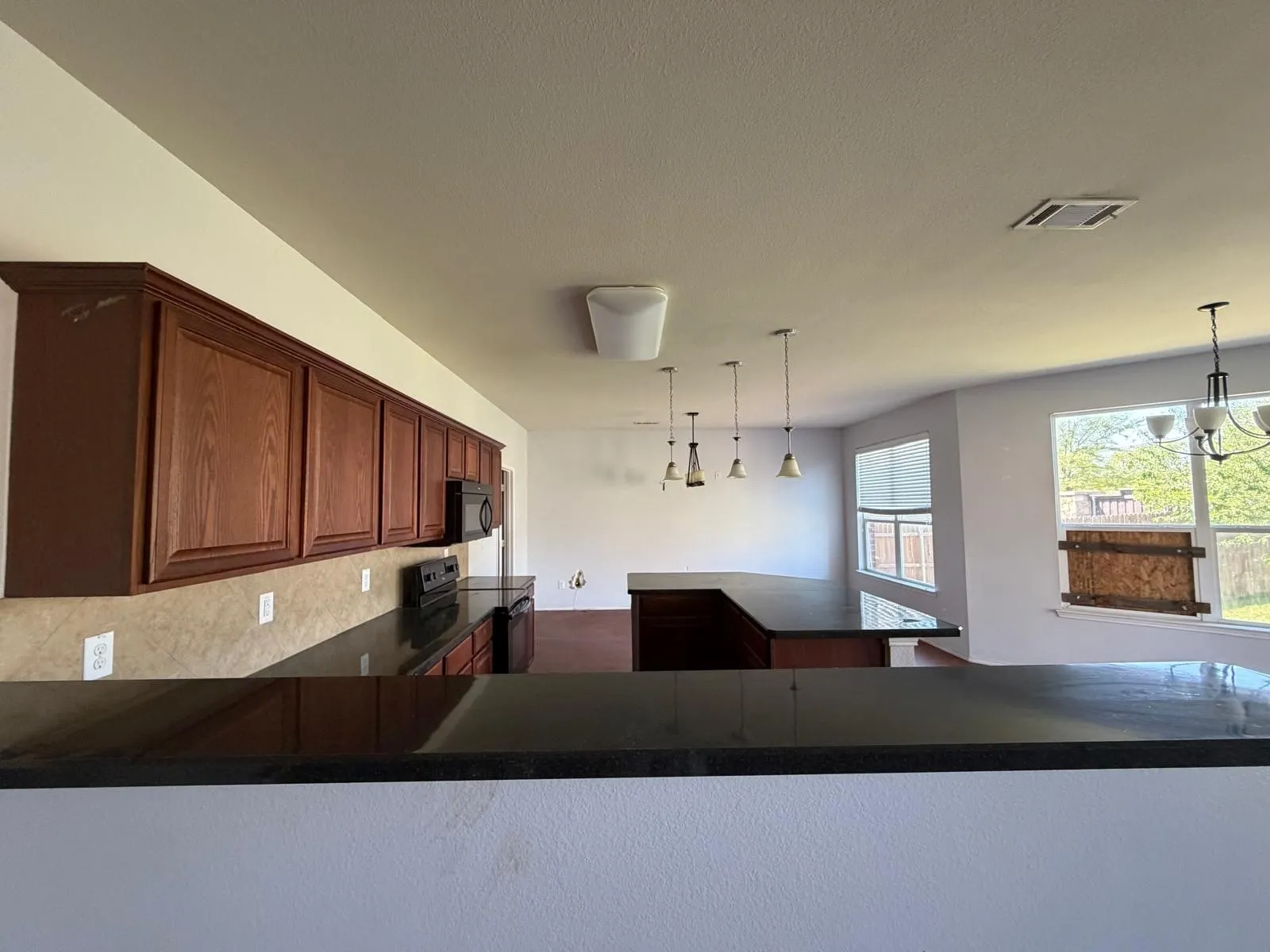 Kitchen with a center island, black appliances, dark stone countertops, and a chandelier