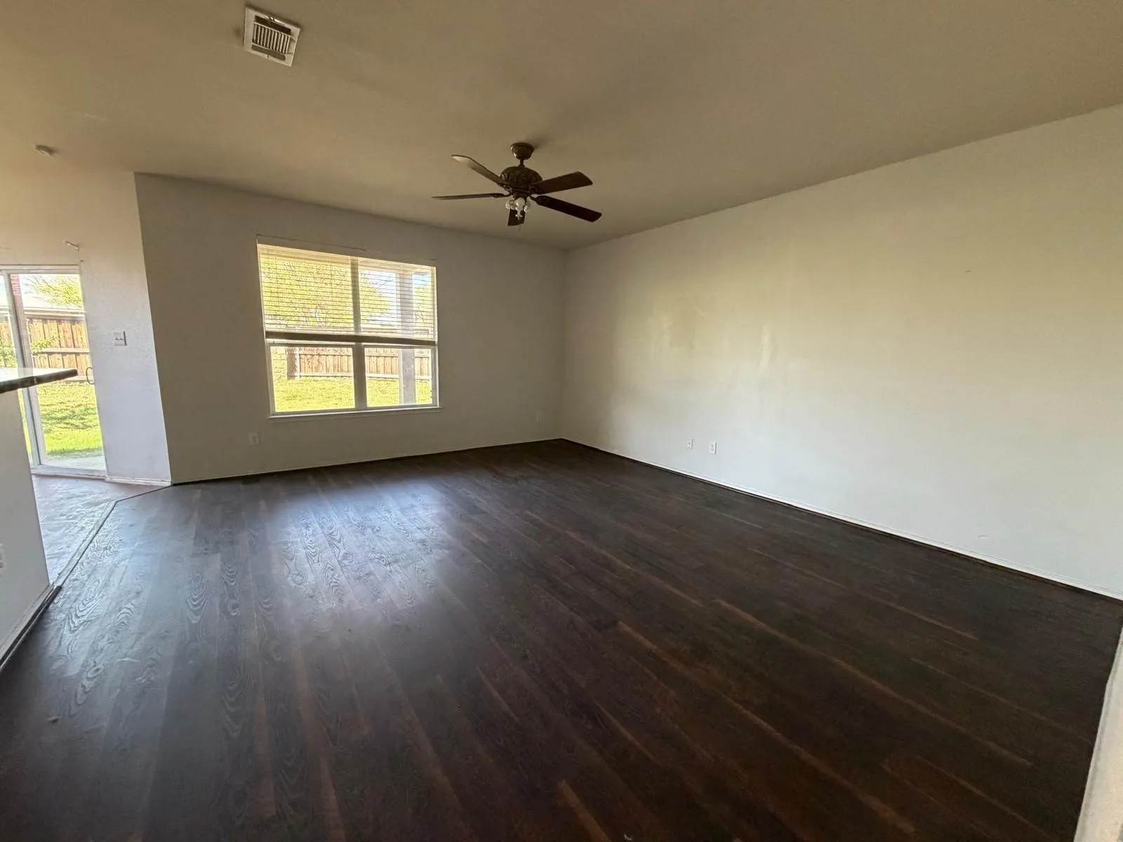 Empty room with ceiling fan and dark wood-style flooring