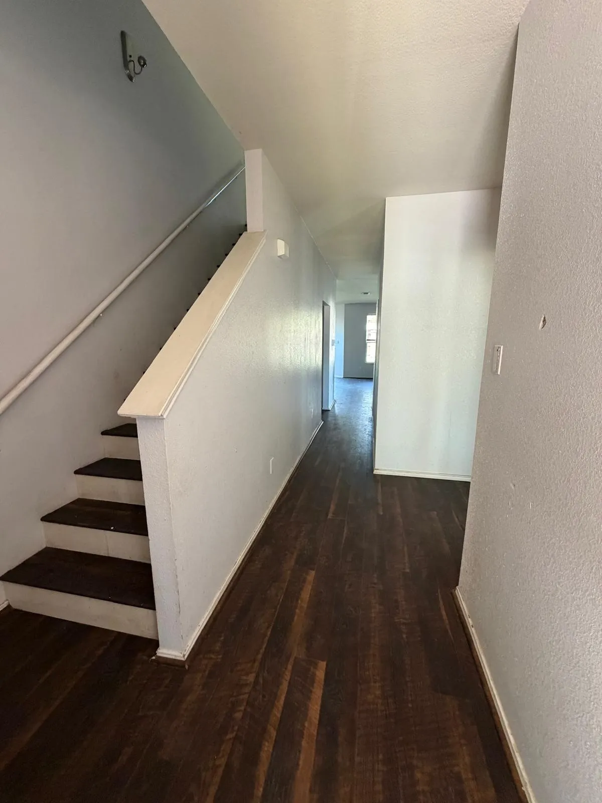Hallway featuring dark wood-type flooring and a textured wall