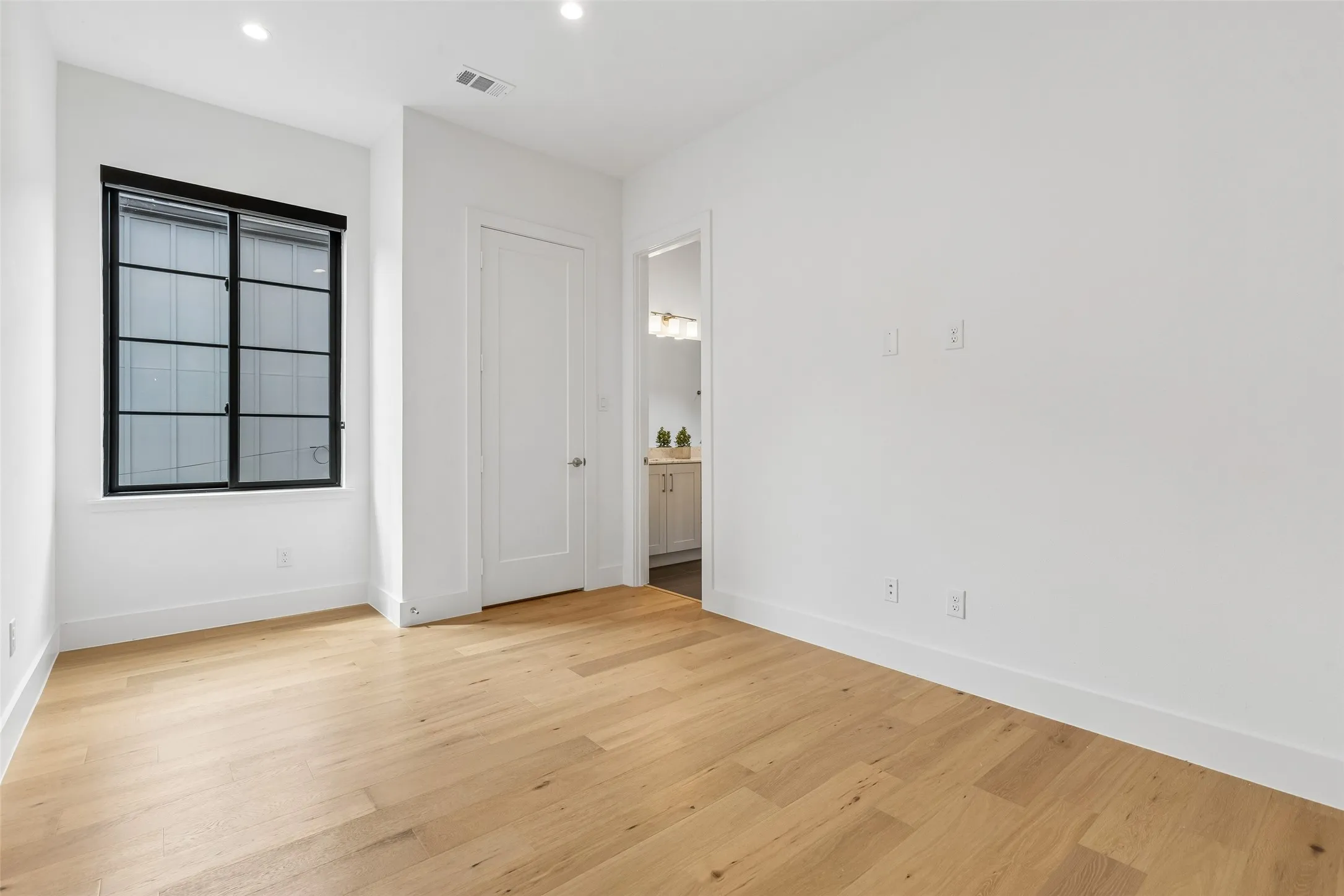 Unfurnished bedroom with light wood-type flooring, ensuite bath, and recessed lighting