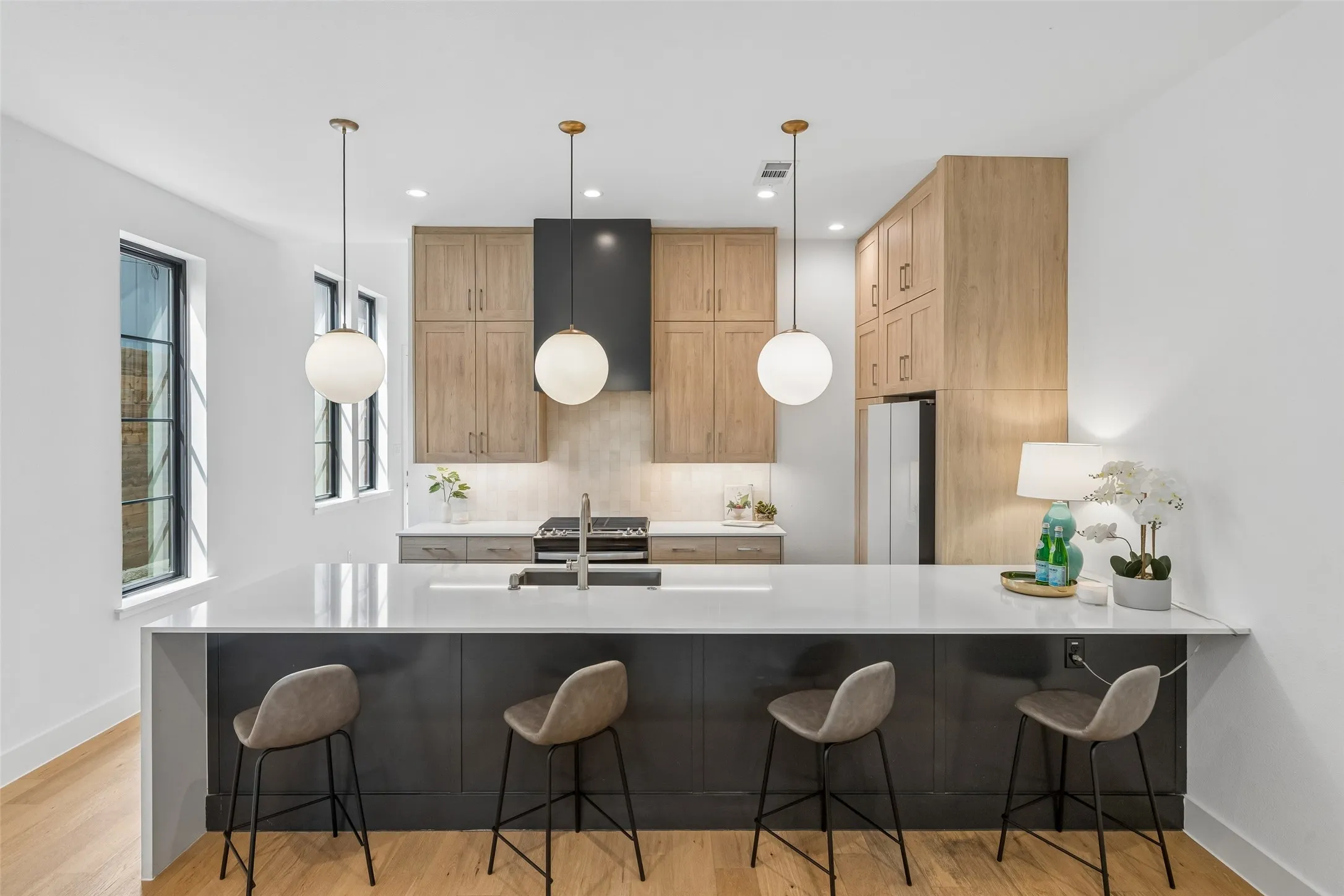 Kitchen featuring a kitchen bar, a peninsula, light stone countertops, and hanging light fixtures