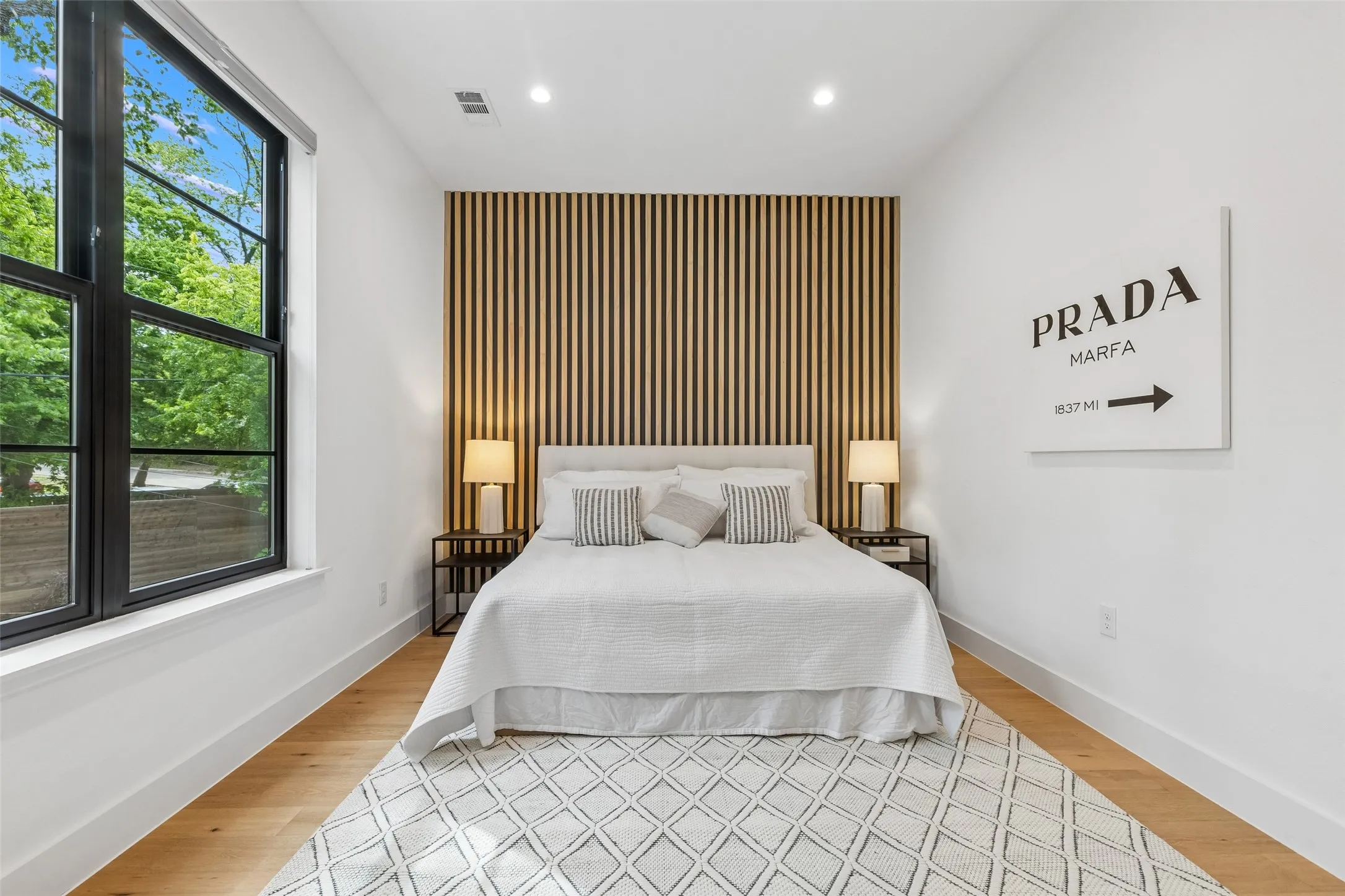 Bedroom with an accent wall, recessed lighting, and light wood-style flooring