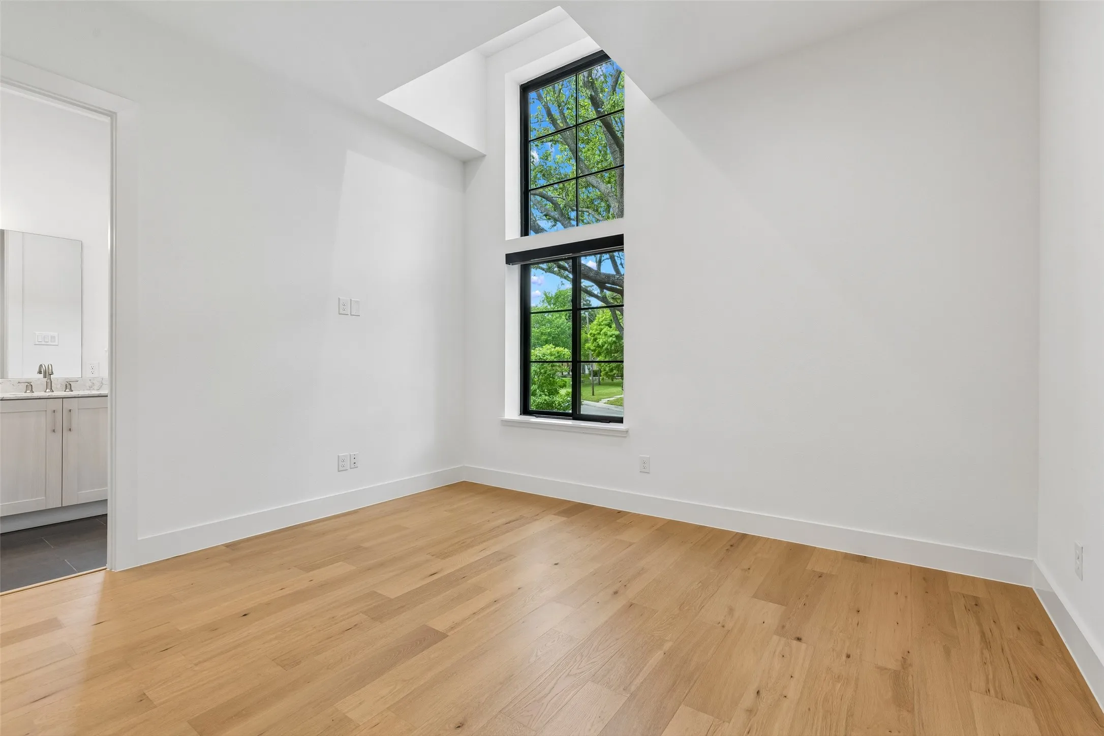 Spare room featuring a high ceiling, light wood-type flooring, and plenty of natural light