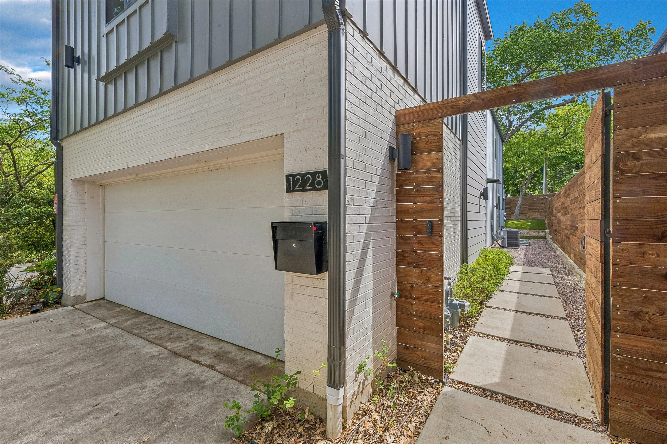 View of side of property with an attached garage, board and batten siding, brick siding, and driveway