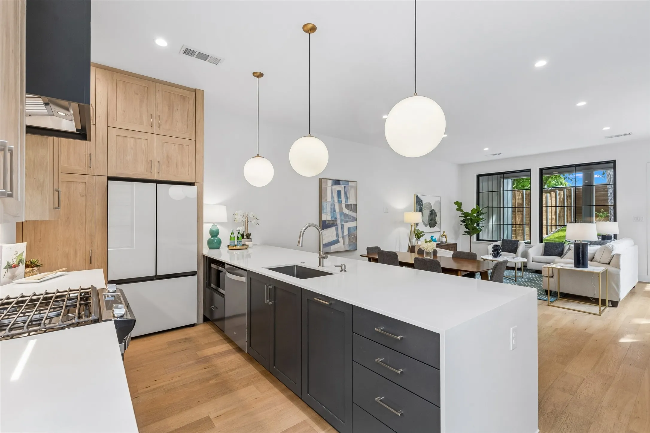 Kitchen with open floor plan, a peninsula, light stone countertops, light wood-style floors, and stainless steel appliances