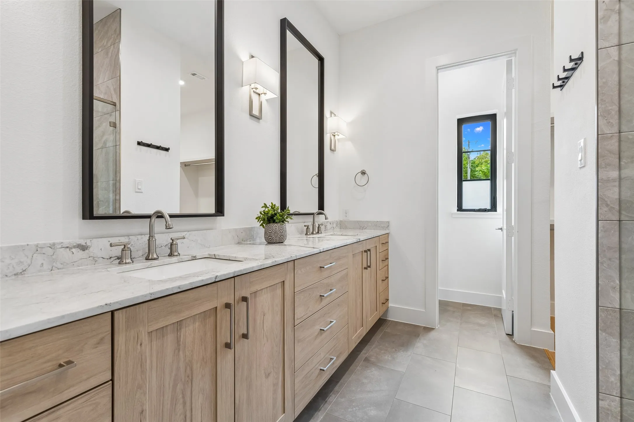 Bathroom with double vanity, tiled shower, and light tile patterned floors