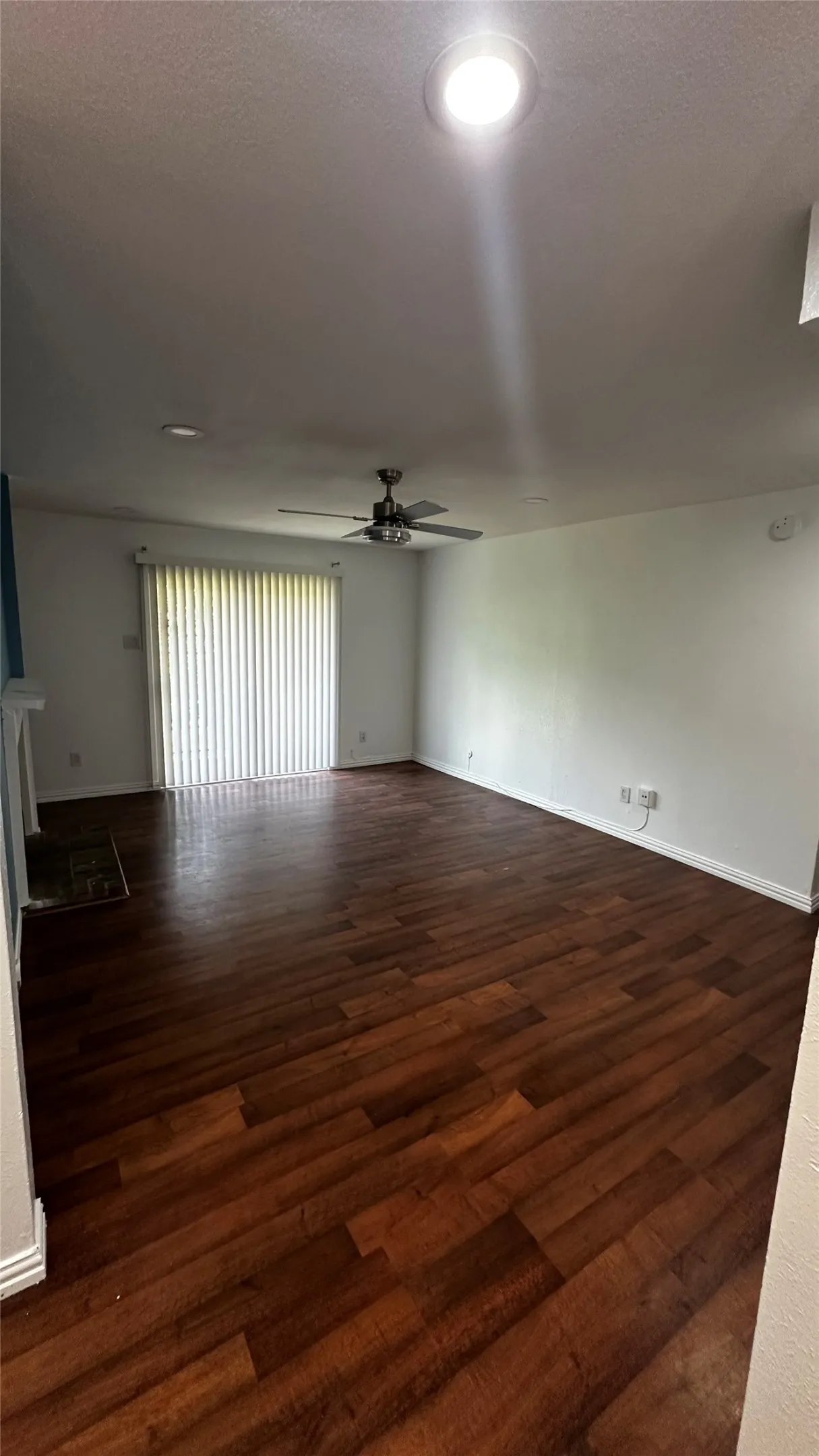 Spacious room featuring wood-finish flooring, a ceiling fan, recessed lighting, and vertical blinds