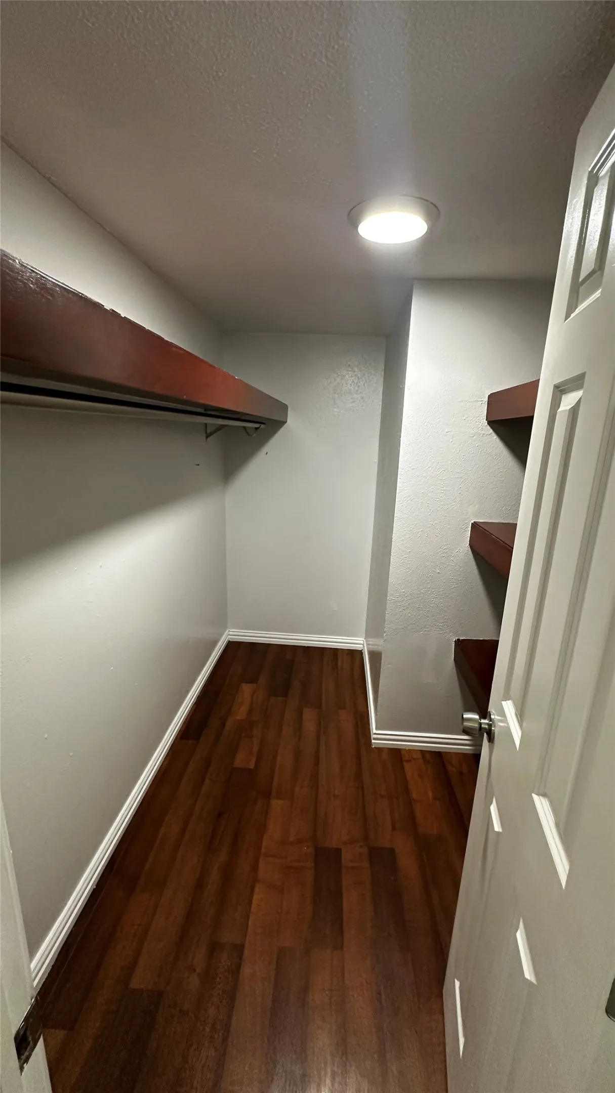 Walk-in closet featuring wood-finish flooring, recessed lighting, and white baseboards