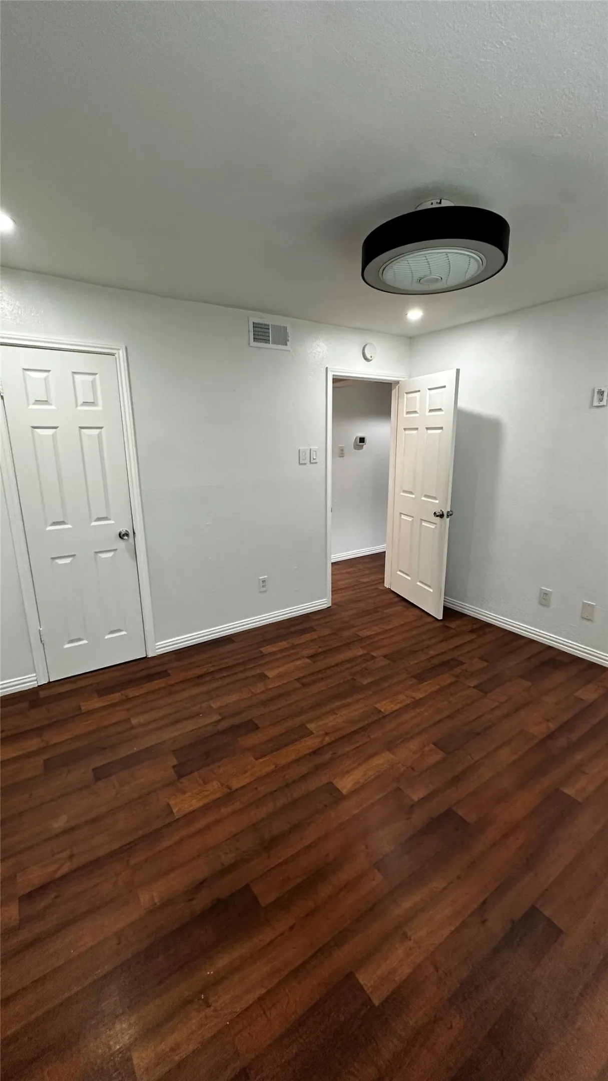 Interior space featuring wood-finish flooring, white walls, and a contemporary ceiling light fixture