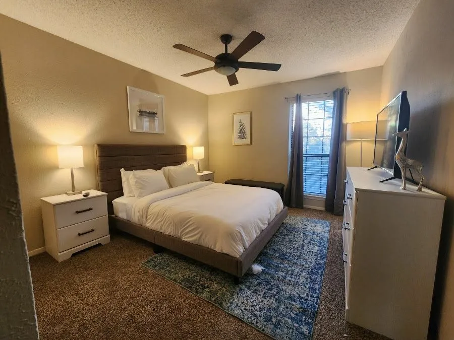 Master Bedroom with dark colored carpet, a ceiling fan, and a textured ceiling