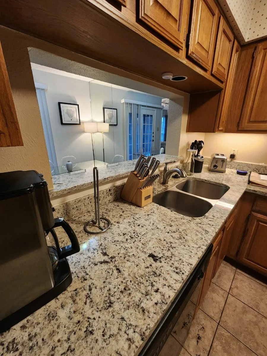 Kitchen featuring wood finish cabinets, light tile patterned floors, and light stone counters