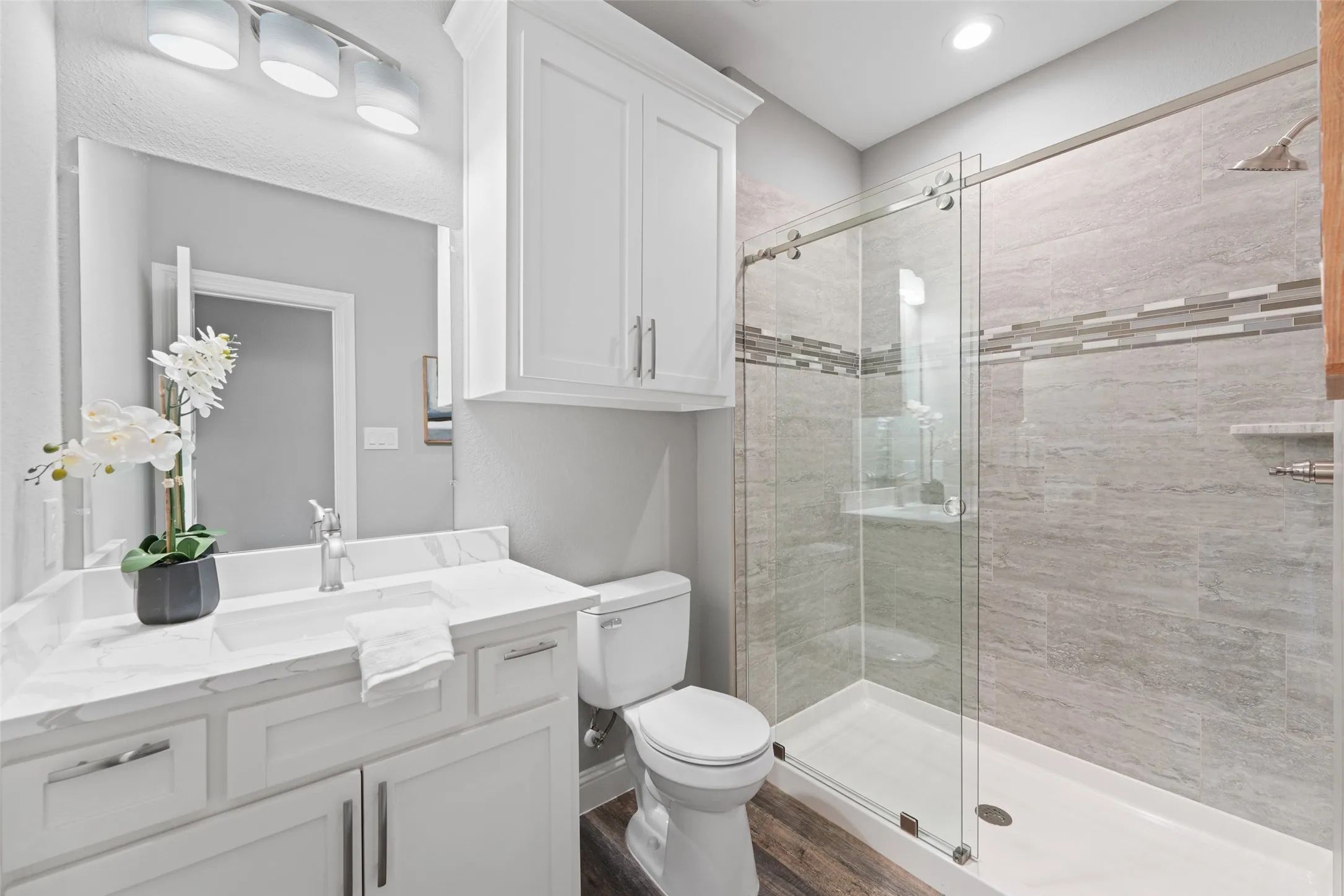 Full bath featuring a stall shower, vanity, and dark wood-type flooring
