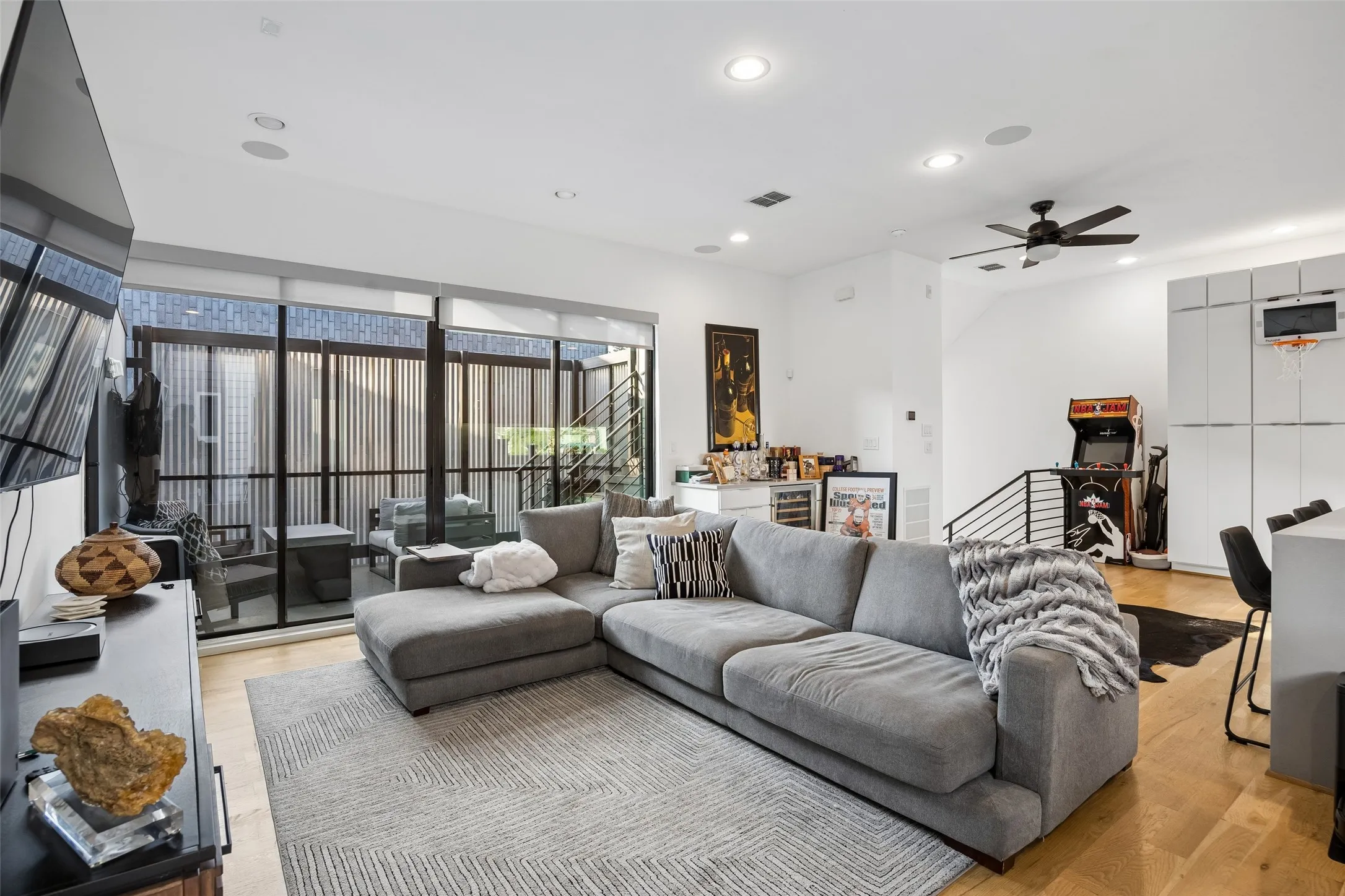 The living area features hardwood floors, recessed lighting, and expansive glass doors opening to an outdoor space