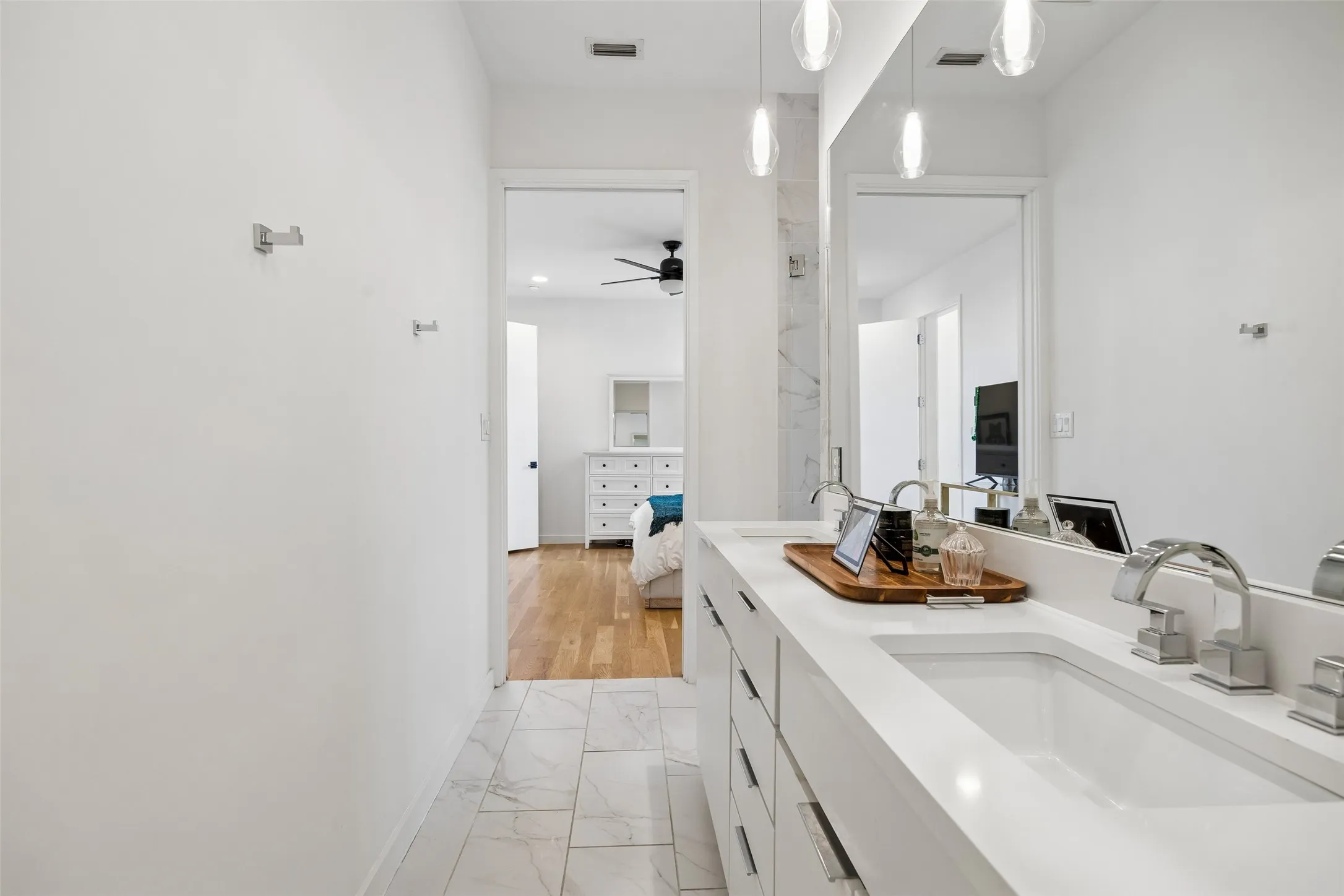 Bathroom featuring a spacious double vanity with two sinks, a large mirror, and tiled flooring