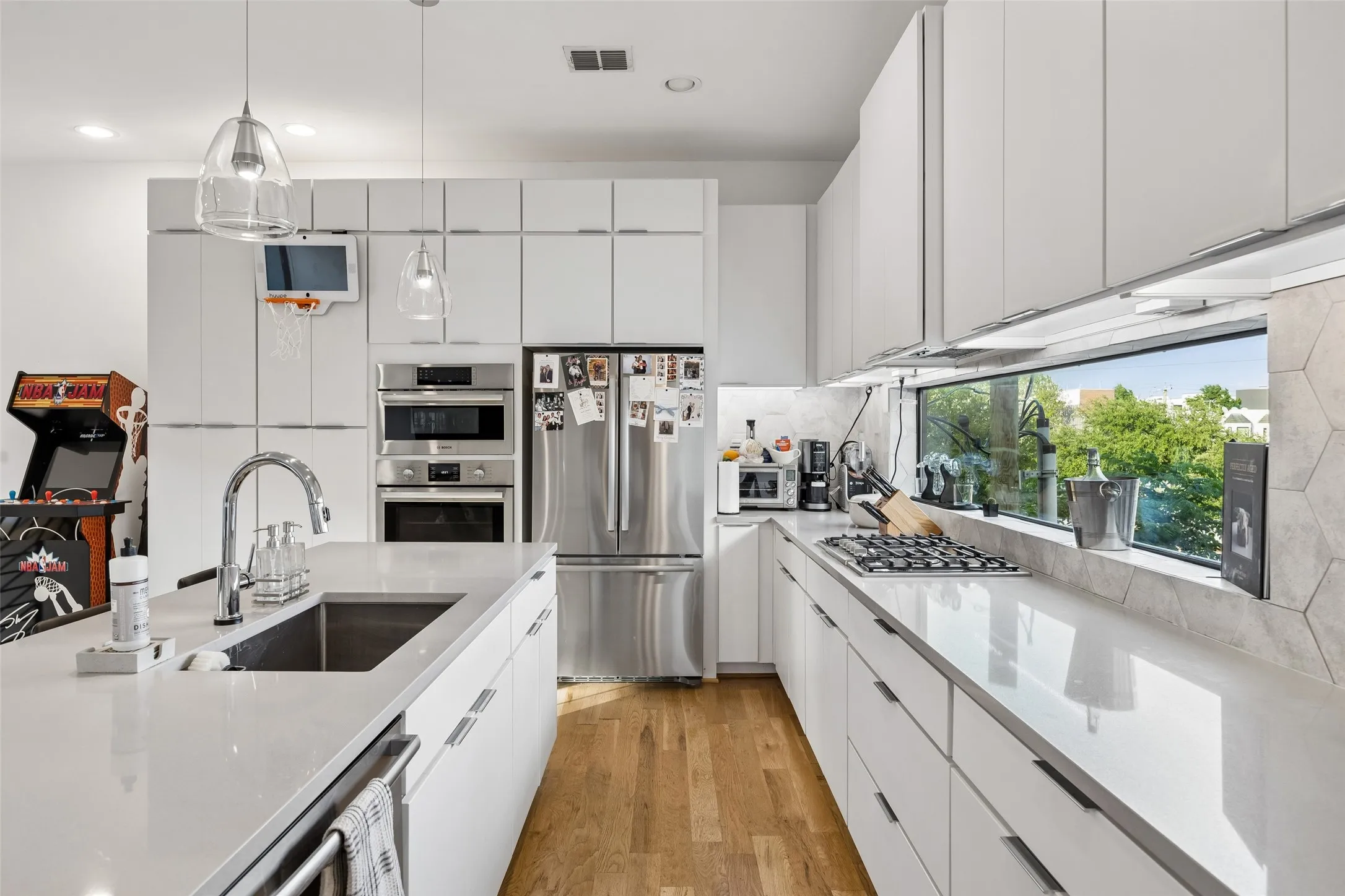 The kitchen features an island with an undermount sink, stainless steel appliances, and extensive white cabinetry